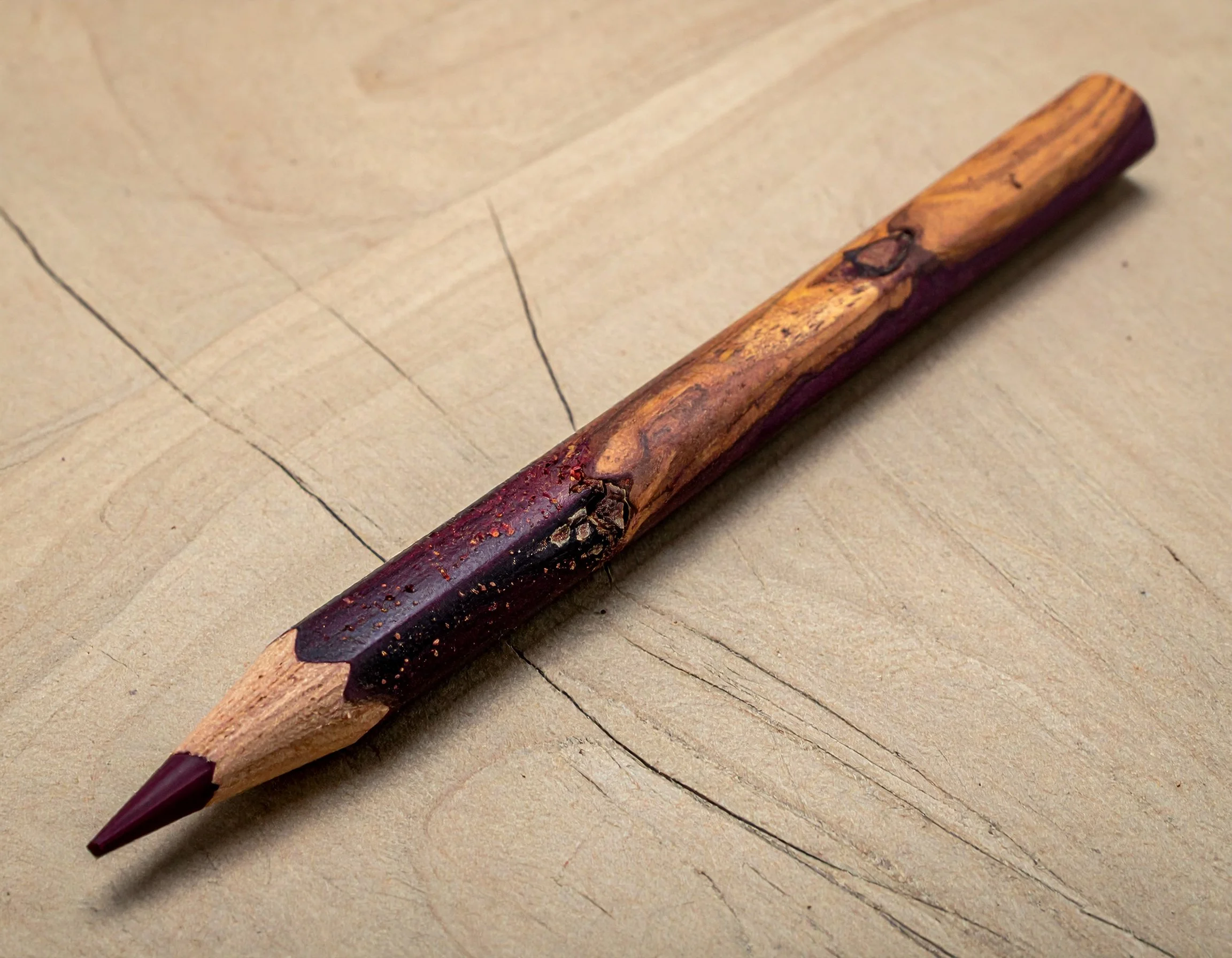 A pen made from a natural branch with the bark partially intact, resting on a wooden surface.