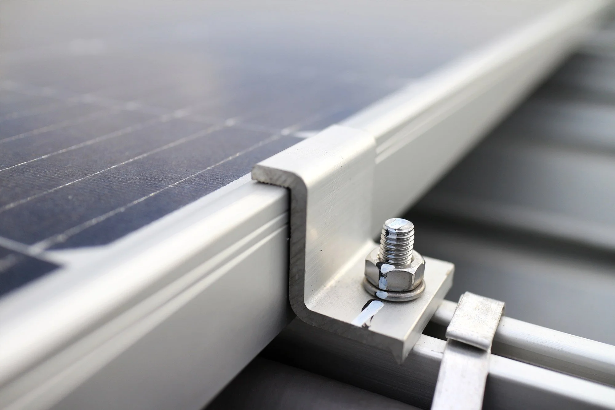 Close-up of solar panels with metal mounting hardware and bolts.