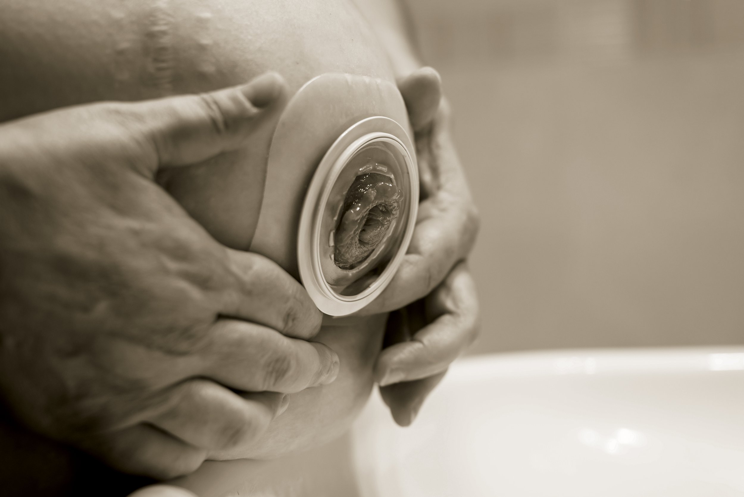 Black and white photo of a person holding a round object with a circular opening, seen from the side.