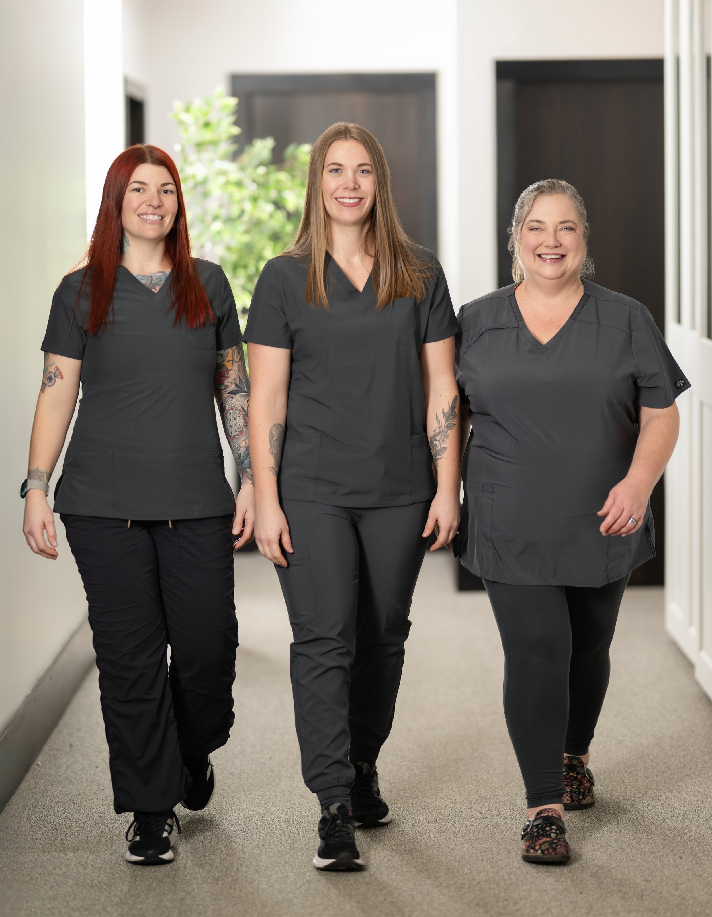 Three women in medical scrubs walking down a hallway.