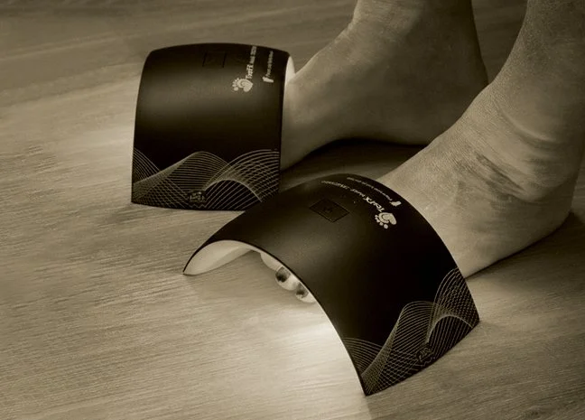 Person's ankles with ankle braces resting on a wooden floor.