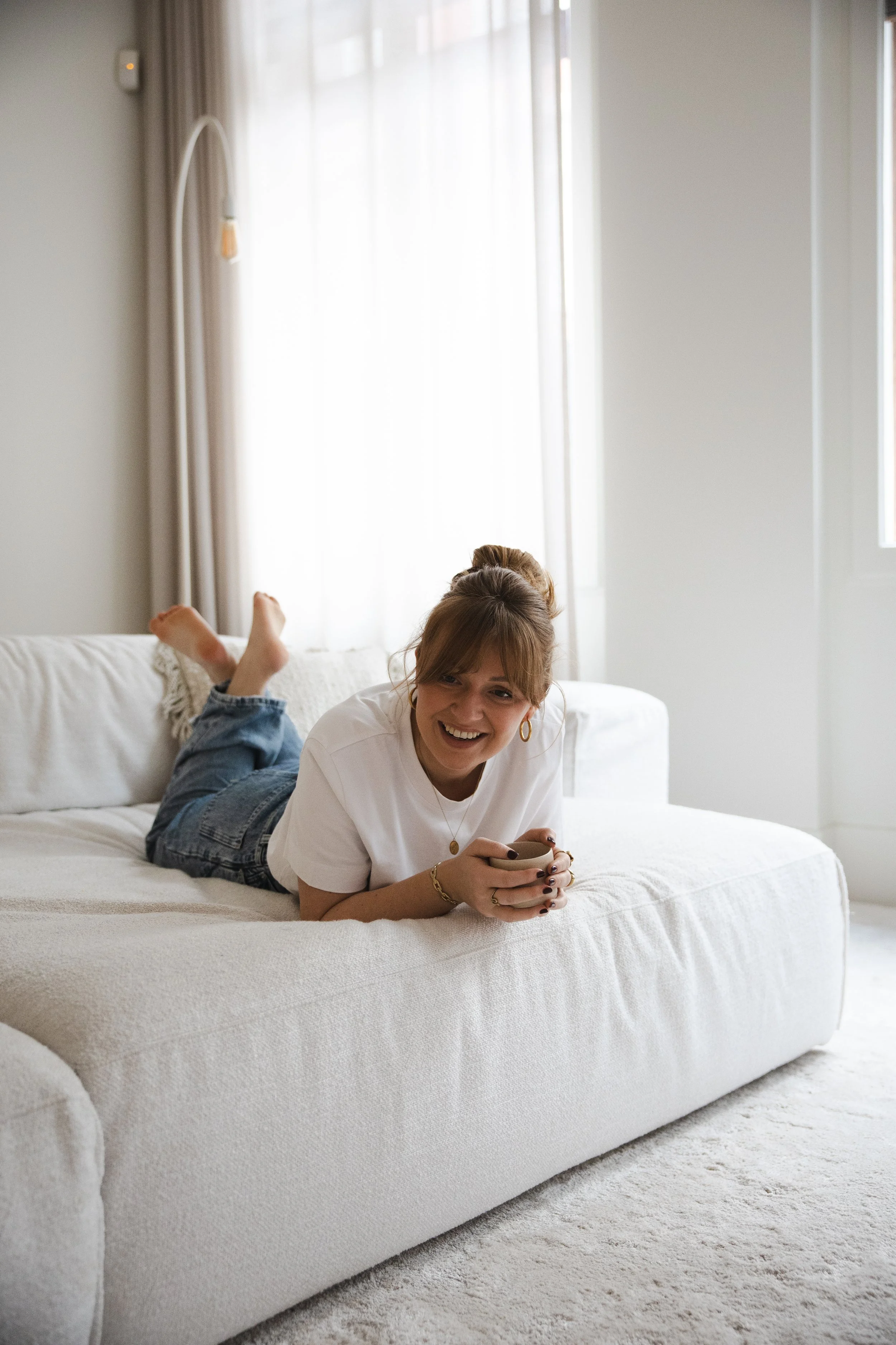 Femke van sorae ontspannen op de bank; een authentiek portret van de vrouw achter het merk die de kracht van vertraging en een relaxed ritme belichaamt.