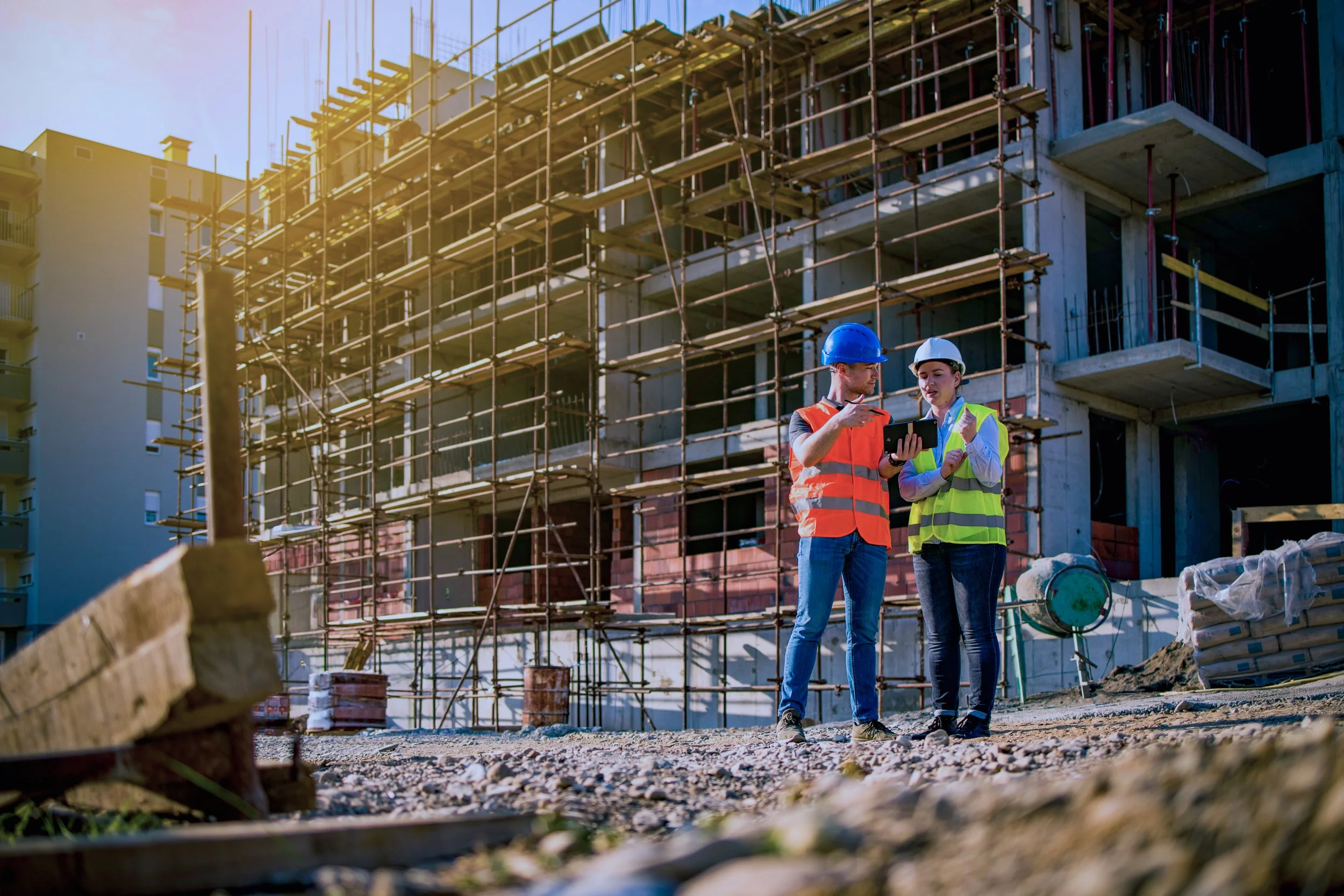 Two construction professionals reviewing project plans on an active construction site.