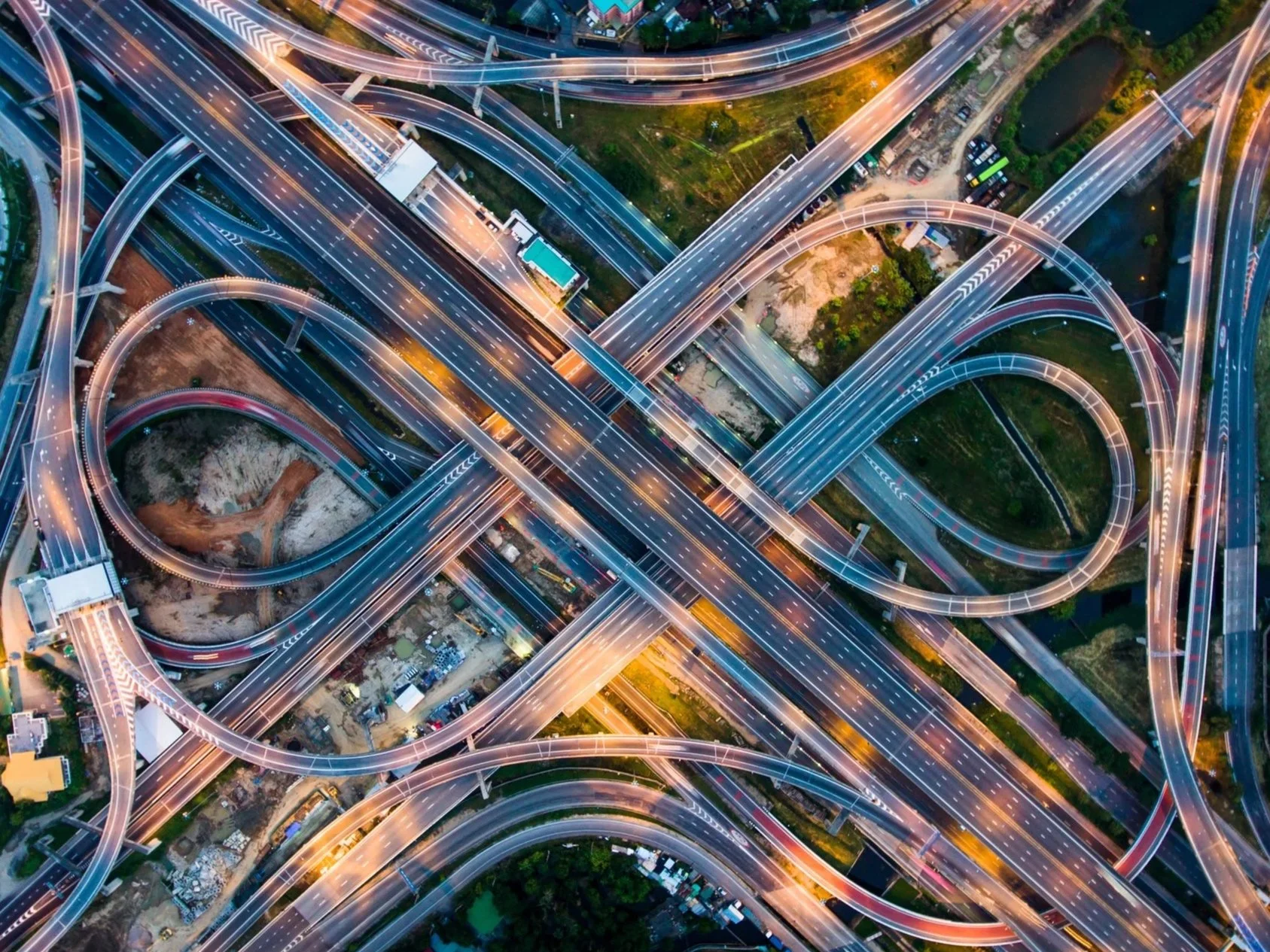 Aerial view of a complex highway interchange with multiple looping ramps and overpasses at dusk.