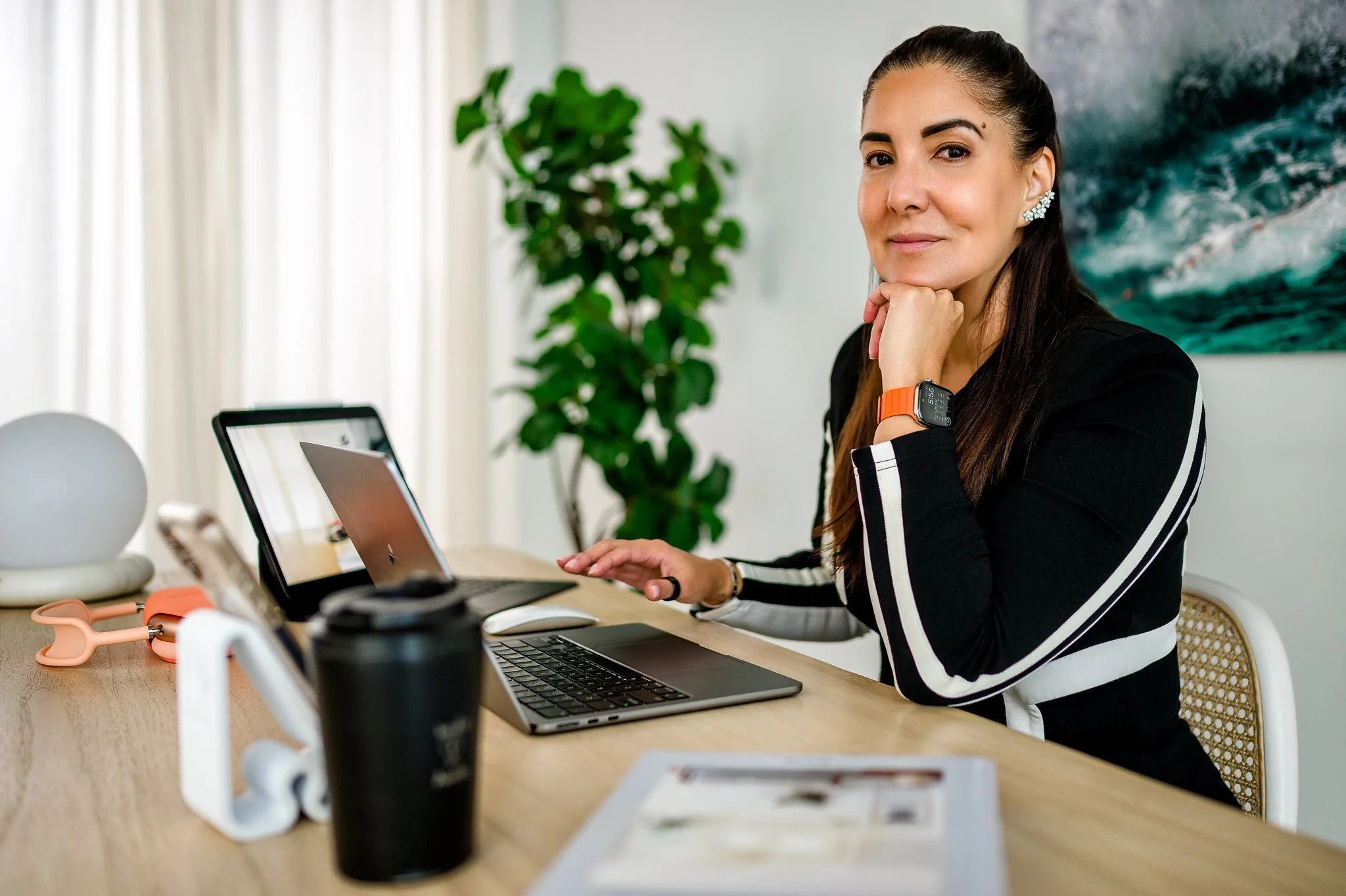 Professional woman working at a desk in a modern office with a laptop and smartphone.
