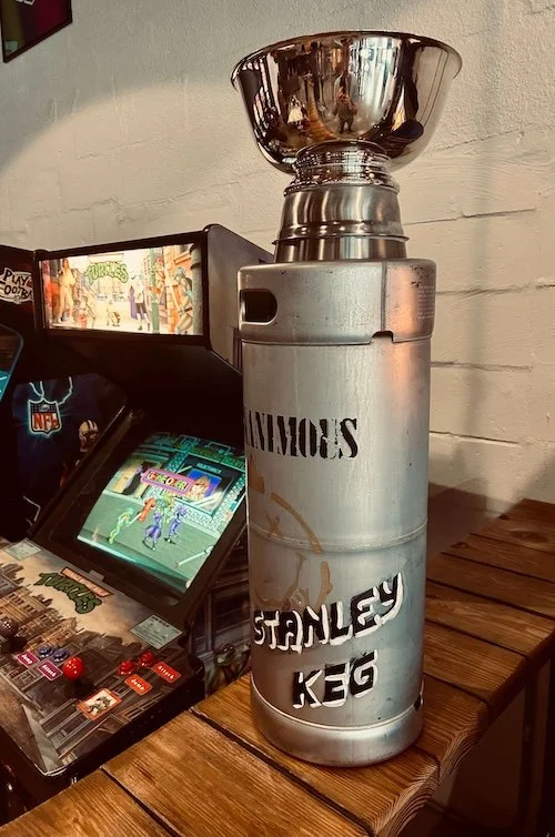 Handmade Stanley keg trophy next to classic arcade game
