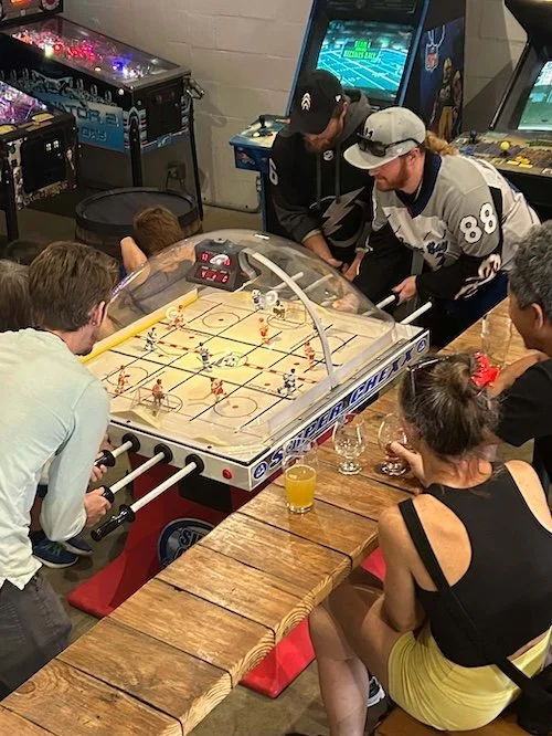 Adults drinking beer and playing bubble hockey