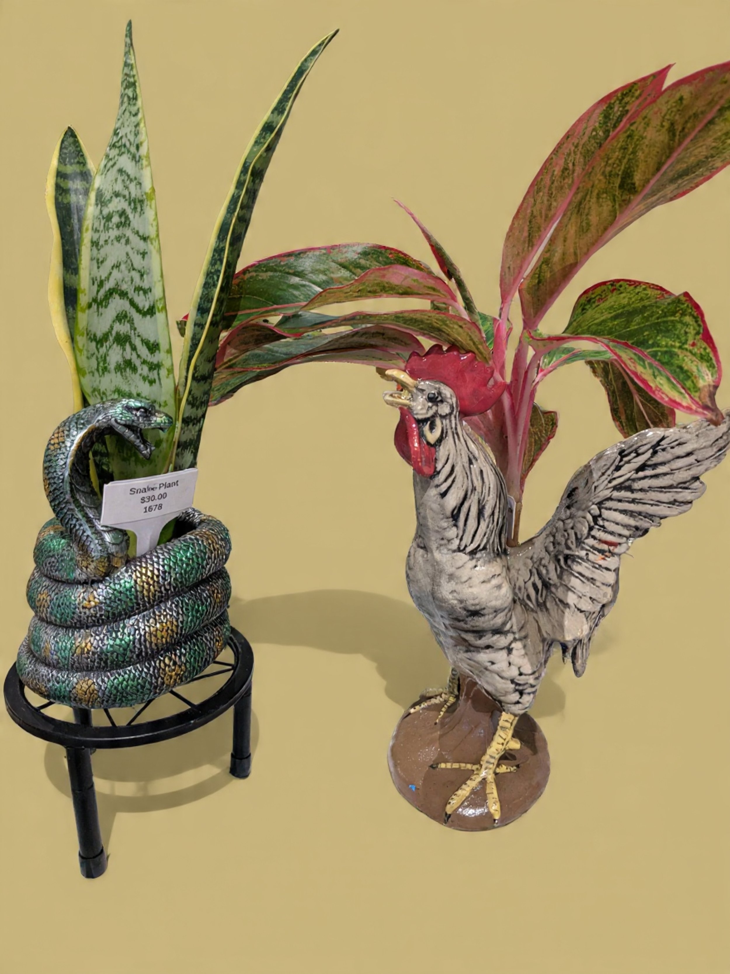 Decorative figurines of a snake and a rooster with fake plants in the background