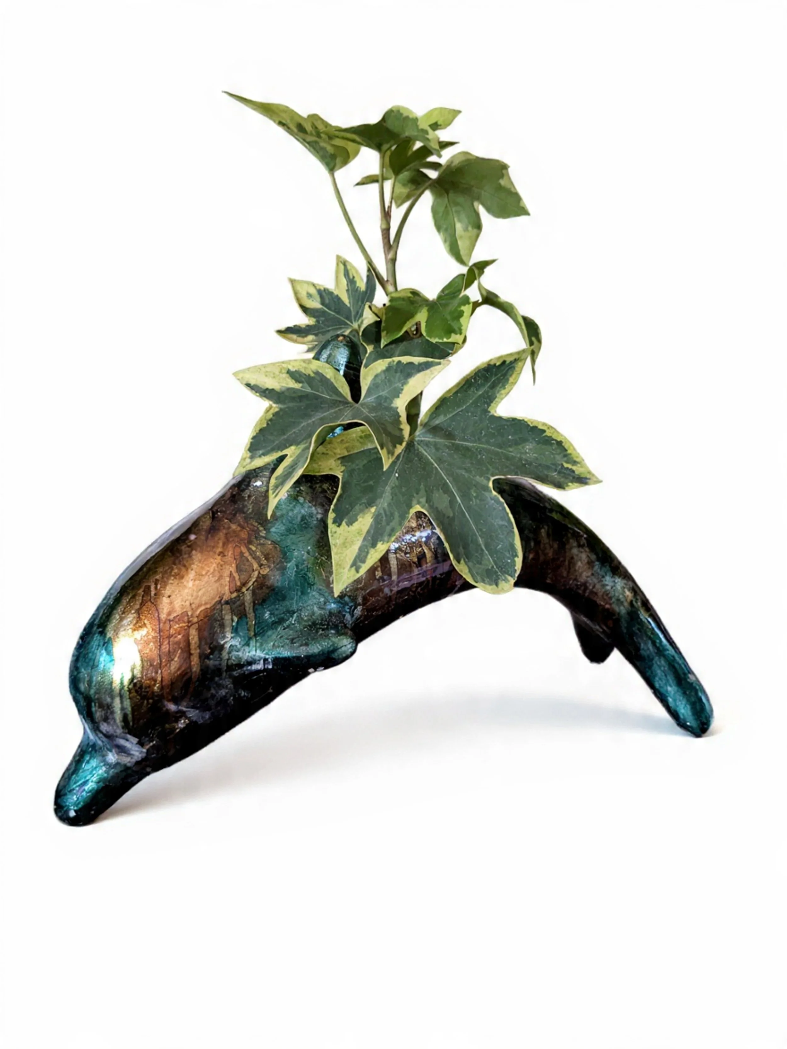 Decorative horse-shaped object with green ivy plant growing out of it, on a white background.