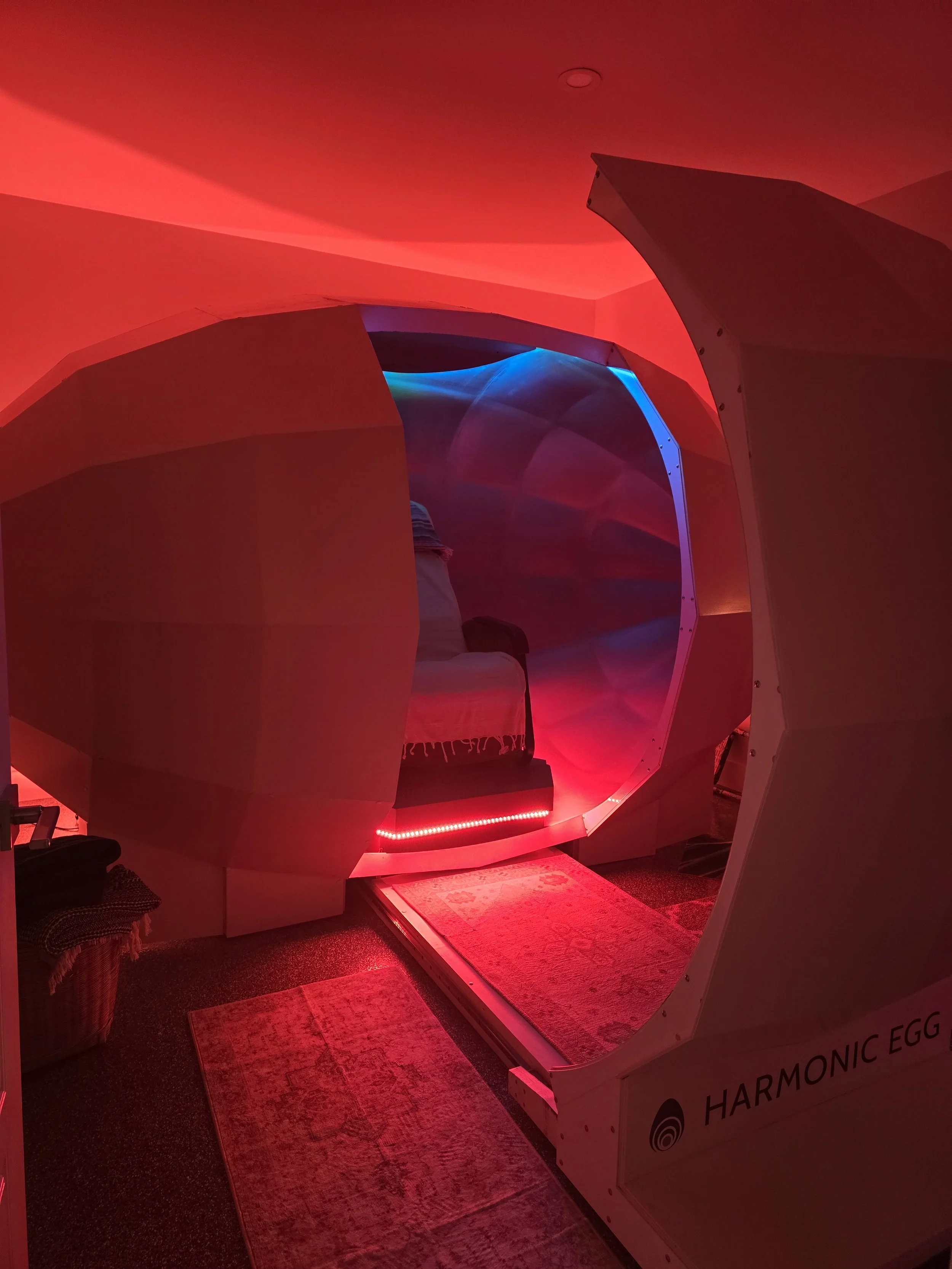An indoor sleep pod called 'Harmonic Egg' with colored lighting and a cushioned seat inside.