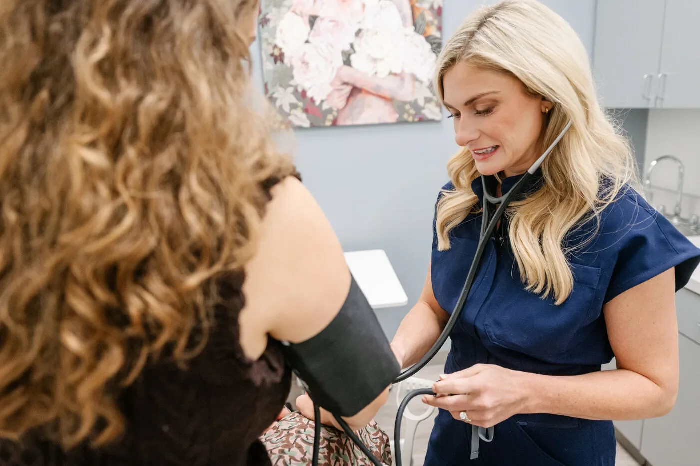 Maggie Theriot, DNP, FNP-C, smiling while checking a patient's blood pressure at Signature Health