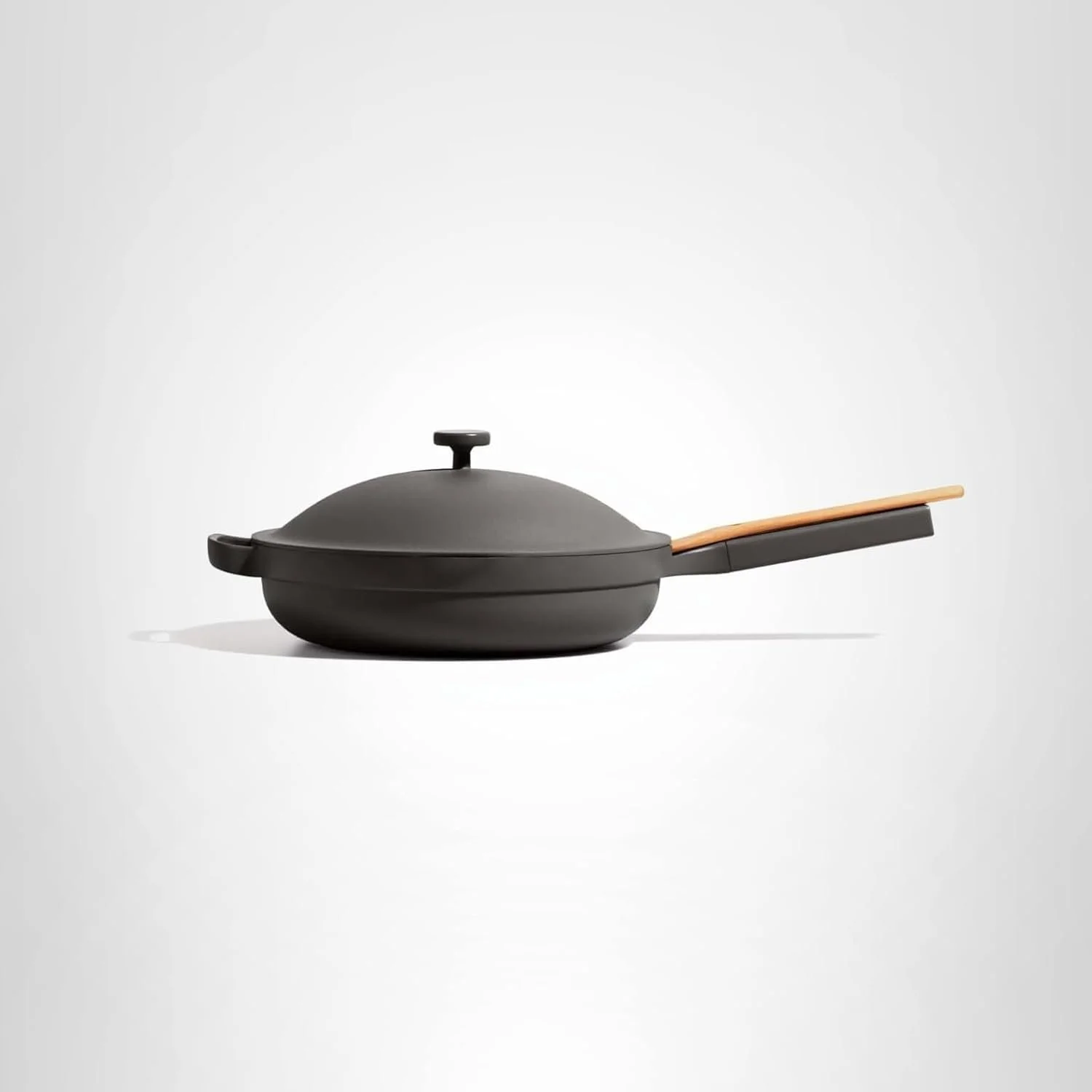 Black ceramic skillet with a lid and wooden handle on a white background.