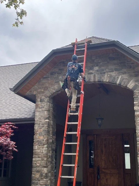 Roof inspection in progress by a professional roofer using ladder safety at a North Idaho home.