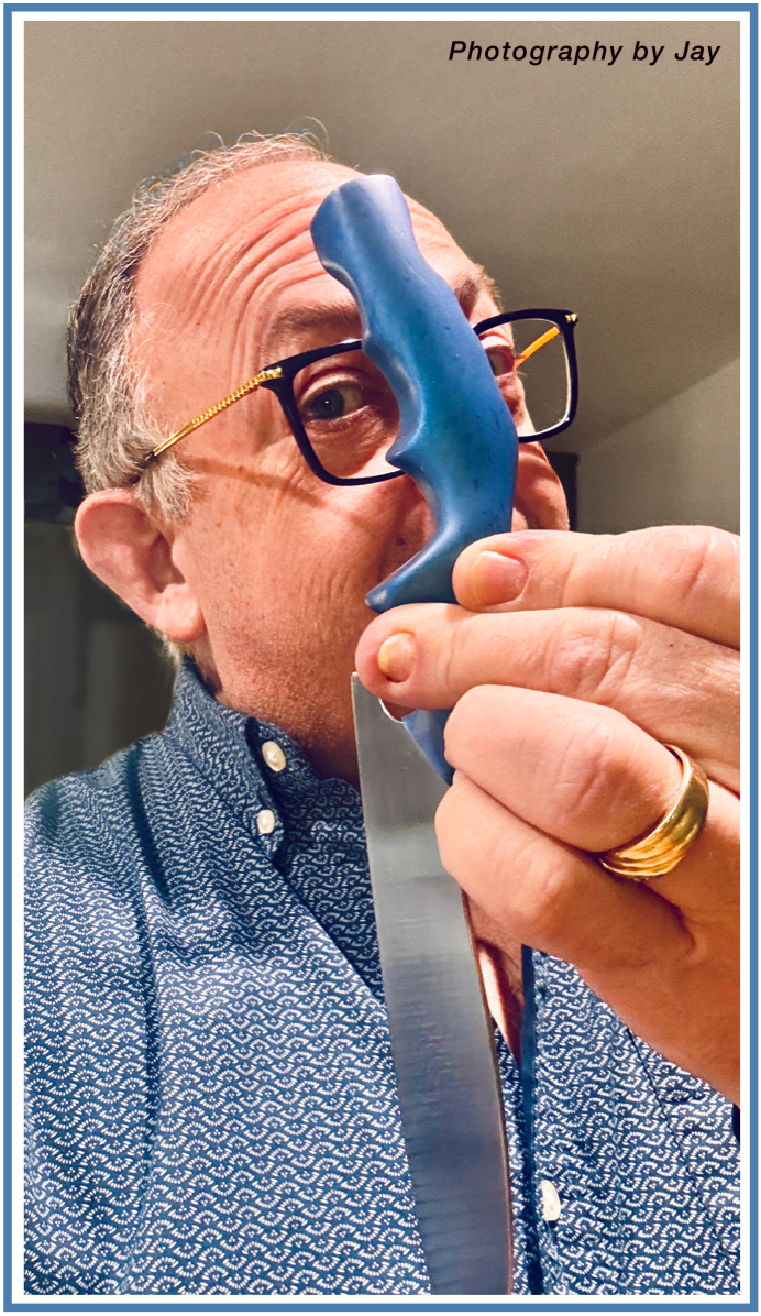 Jay Goldberg Ukulele Jay BBQ national award winning BBQ chef holding blue DBx chef knife