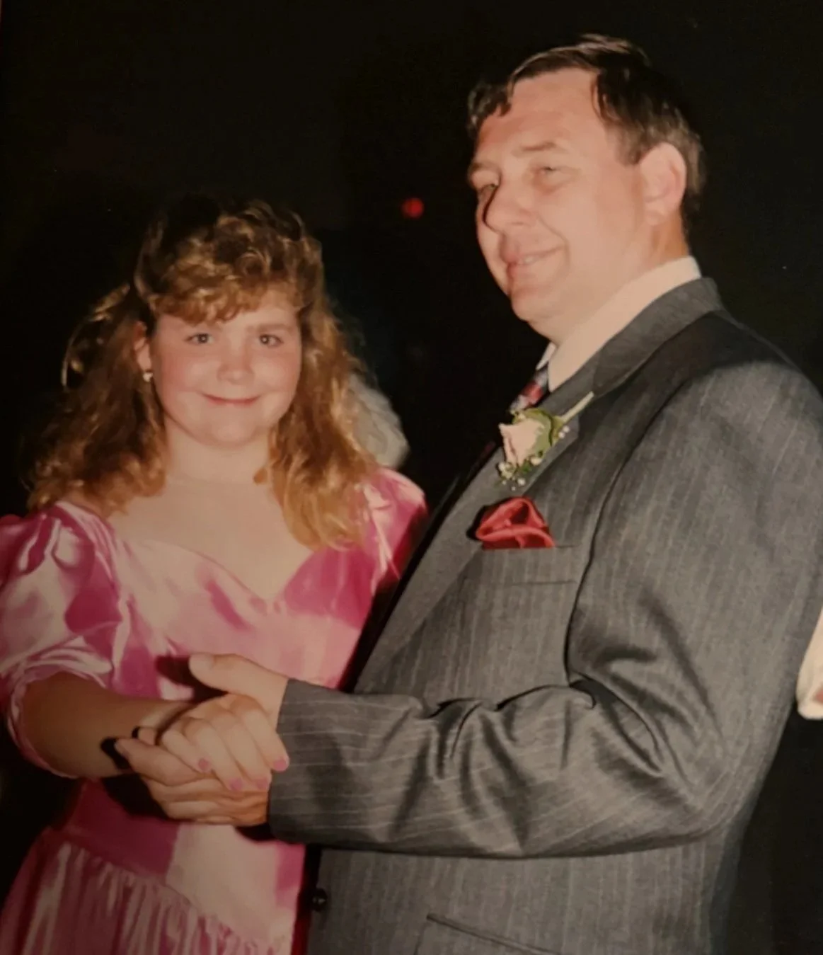 Lisa in grade seven in a pink bridesmaid's dress dancing with a man in a grey suit.