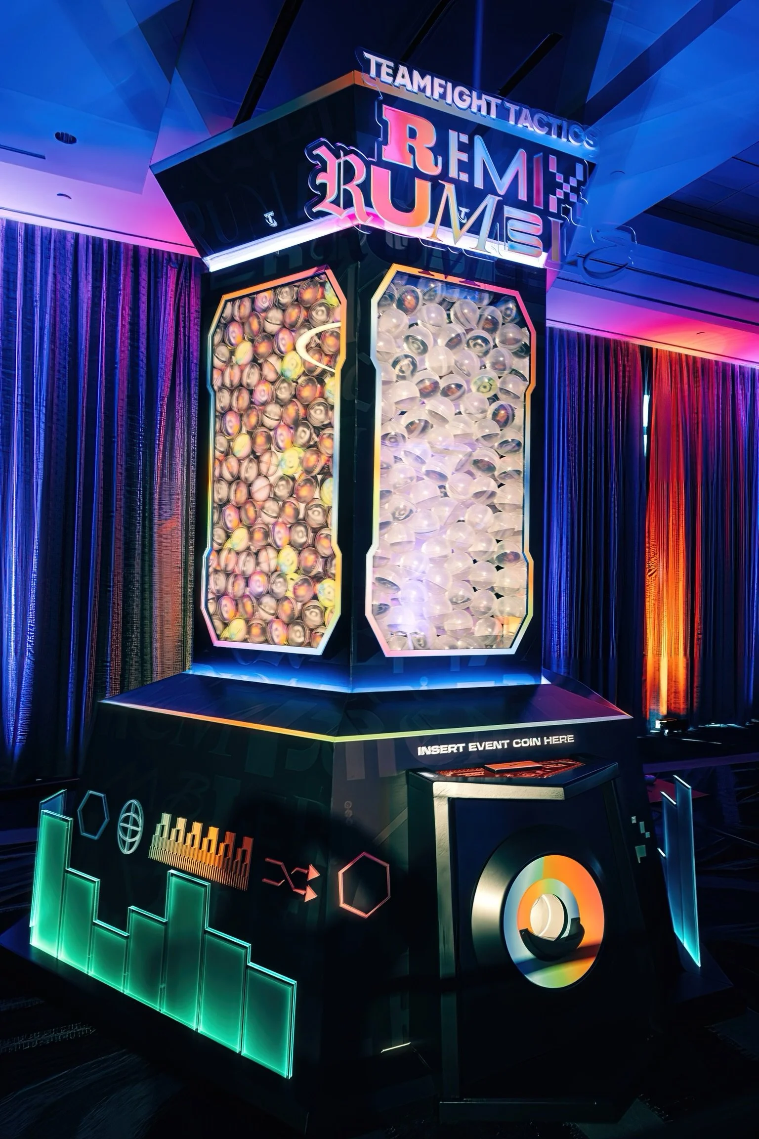 A neon-lit entertainment game machine called 'Teamfight Tactics Remix' featuring two transparent compartments filled with small balls, one with marbles and the other with transparent spheres, with vibrant colorful lights and music-themed graphics aro