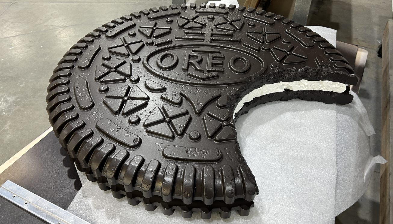 Chocolate Oreo cake with a slice removed, revealing white cream filling, on a silver surface.
