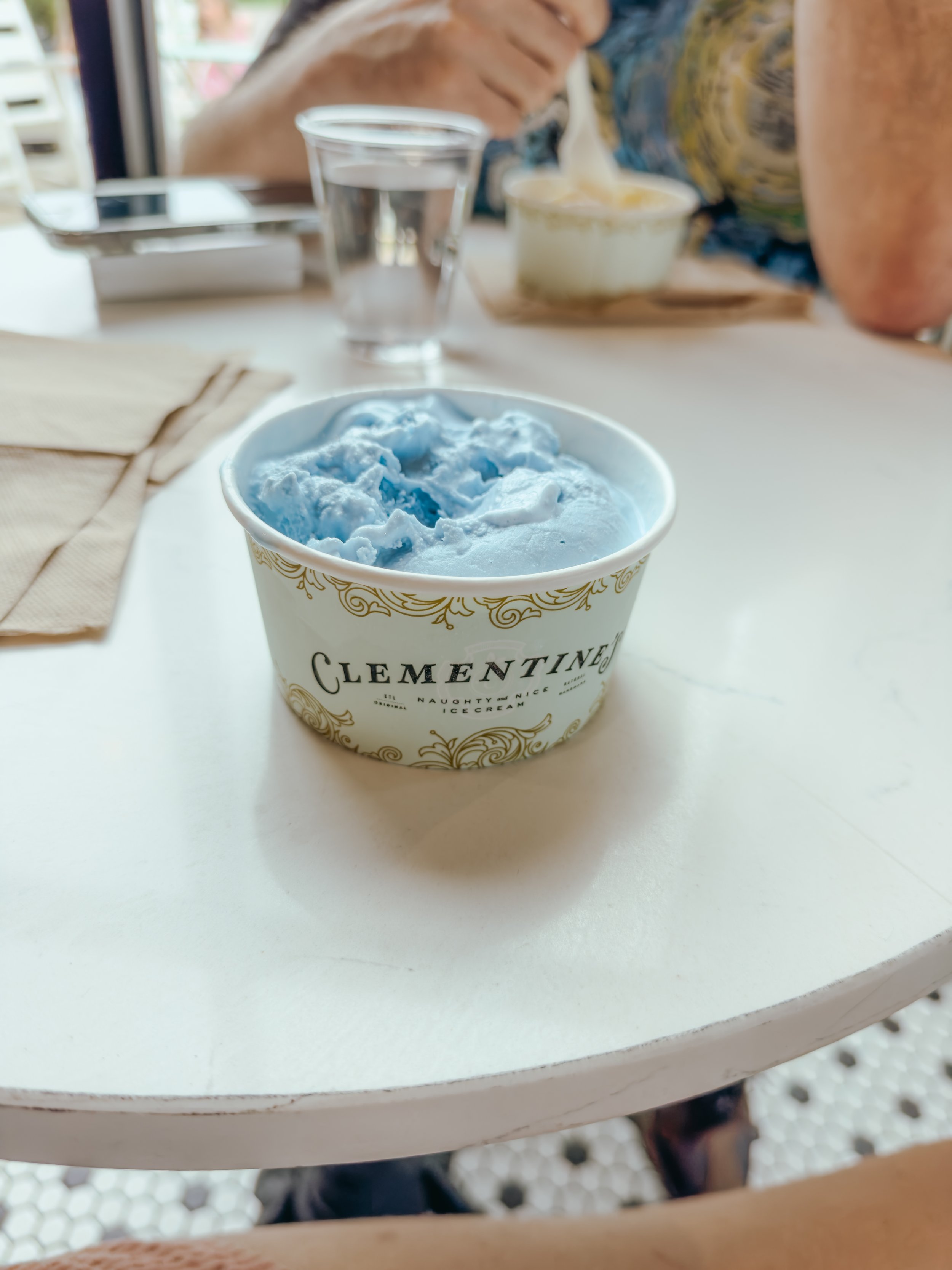 A cup of blue ice cream on a white table at a cafe.