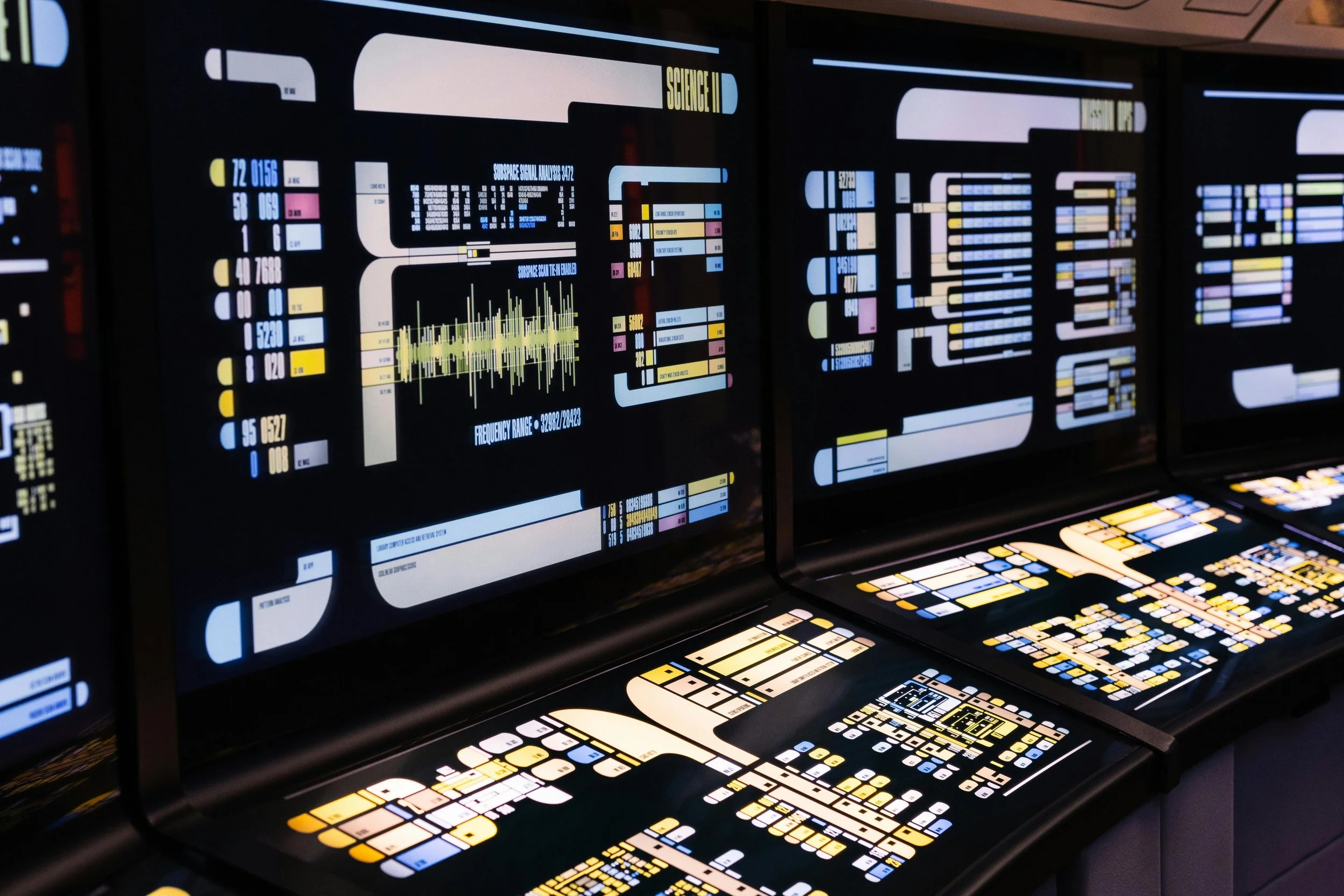 Star Trek-style computer console with multiple monitors displaying colorful futuristic graphics and data.