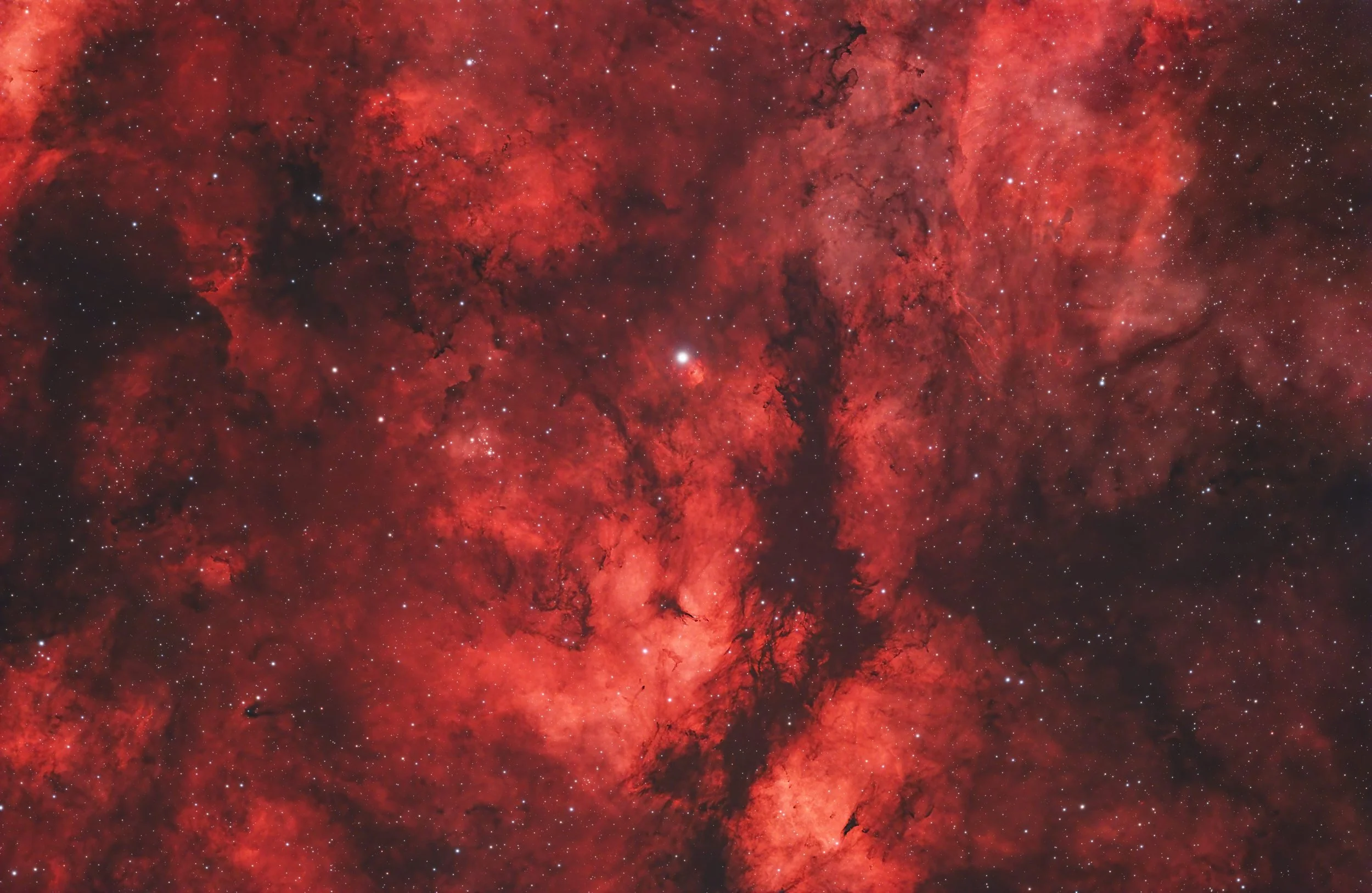 A vivid red and black nebula with numerous stars scattered throughout the image.