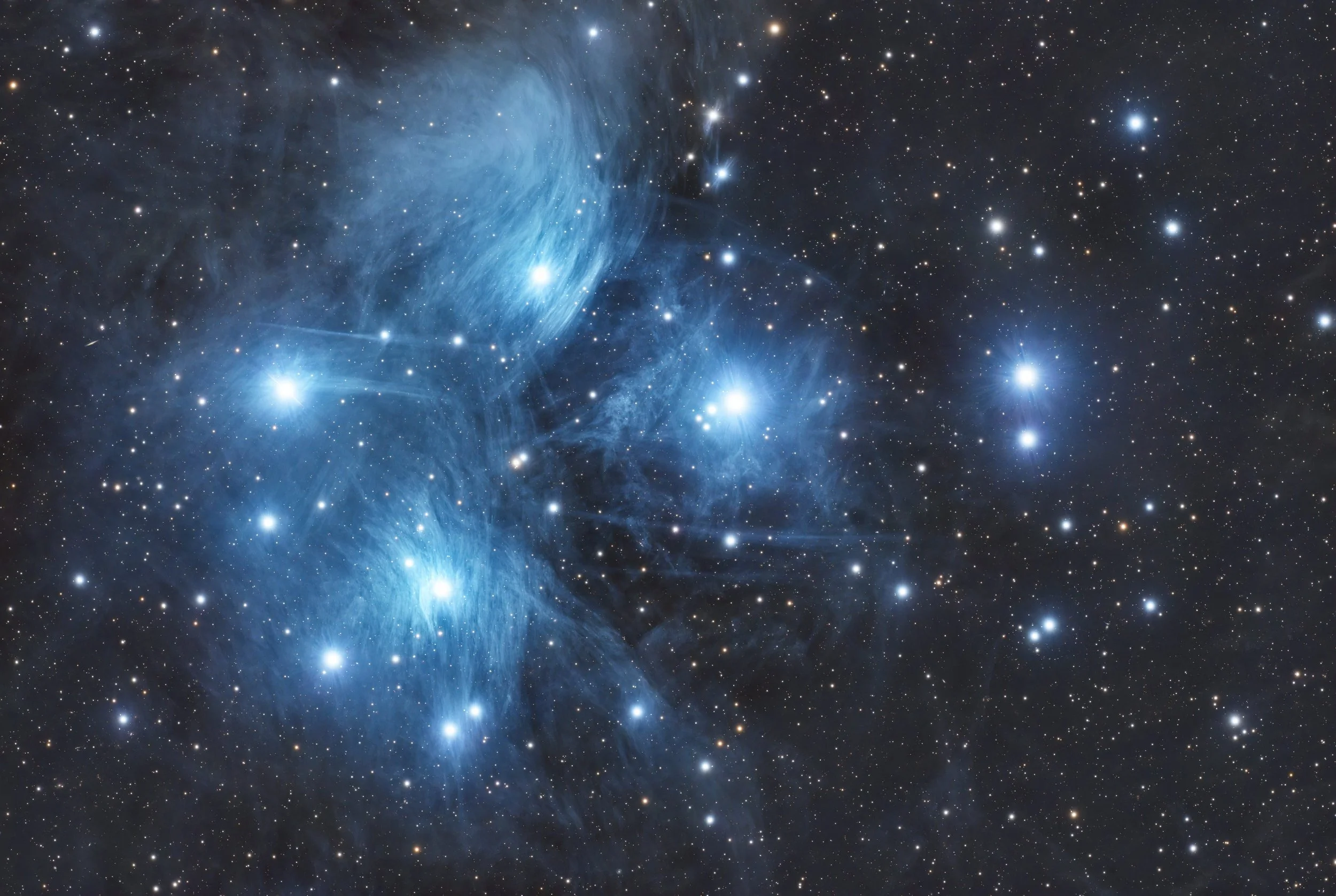 A detailed image of a star cluster in deep space with numerous bright stars, blue nebulae, and gas clouds surrounded by numerous smaller stars.