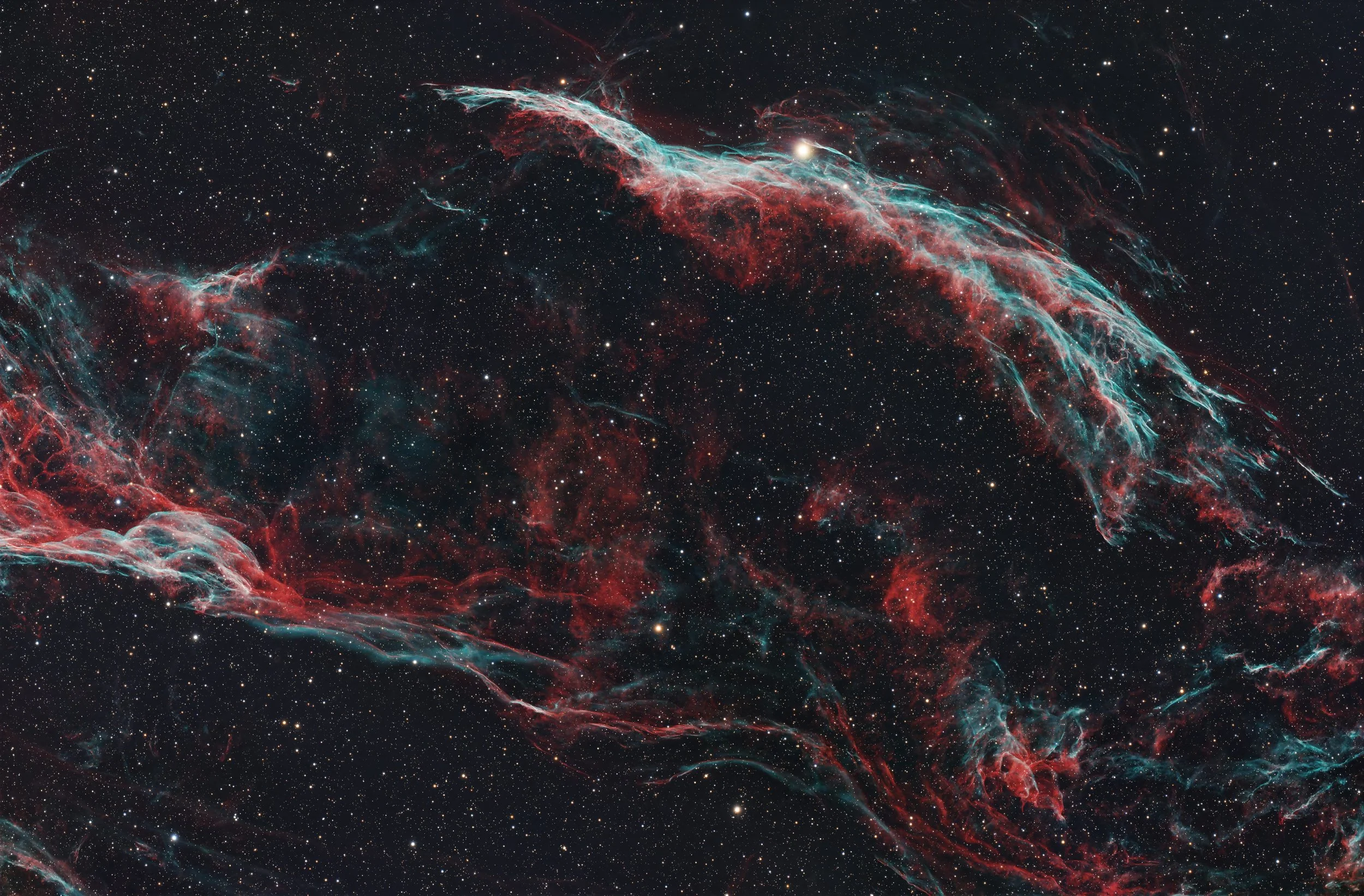 A colorful image of a nebula in space with red and blue gaseous formations and numerous stars in the background.