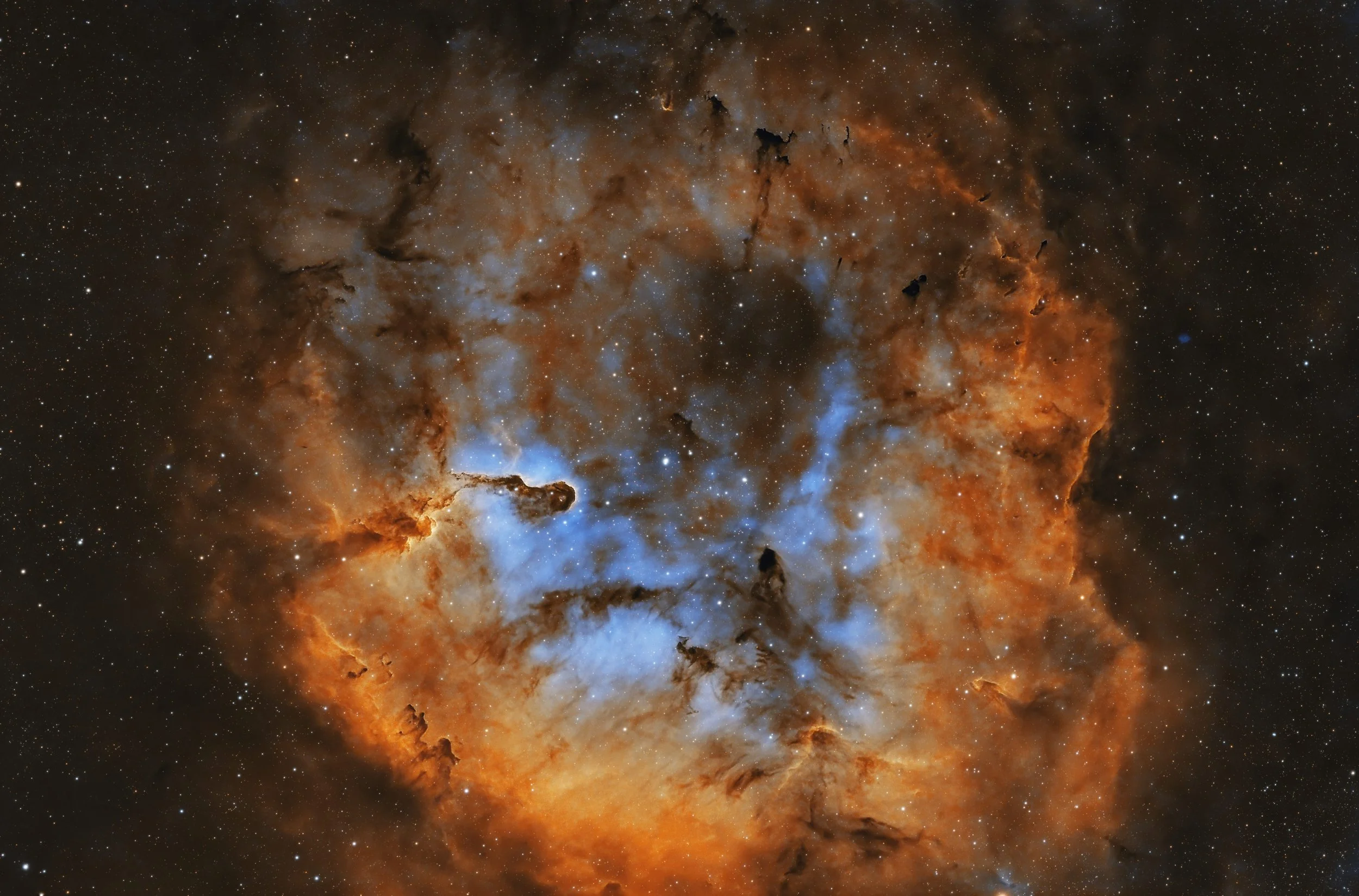 Deep space image of the Orion Nebula, showing bright stars, orange and blue gas clouds, and dark dust lanes.
