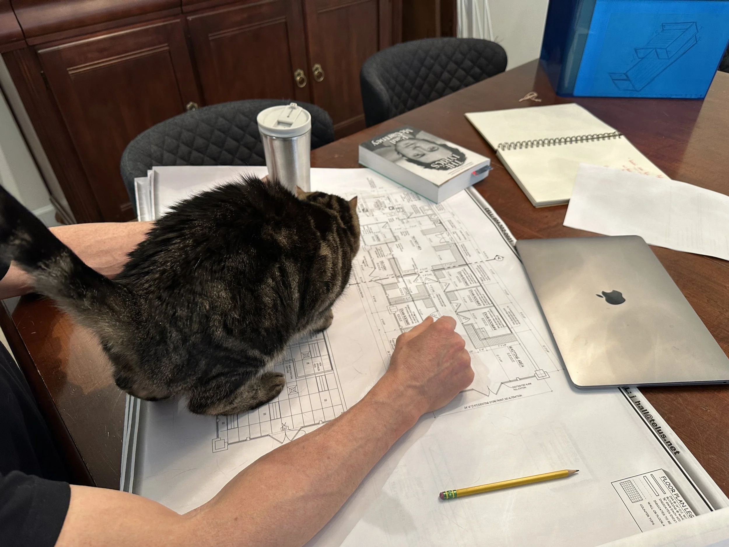 Dr. Art Ceballos and his trusty cat side-kick pour over the new clinic blueprints and documentation.