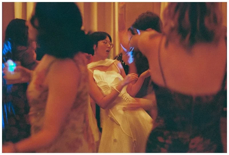 Group of women dancing and socializing at a party or celebration, with some wearing glow-in-the-dark accessories in a dimly lit room.