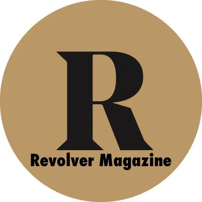 Logo for Revolver Magazine featuring a large black letter 'R' and the magazine's name underneath on a gold circular background.