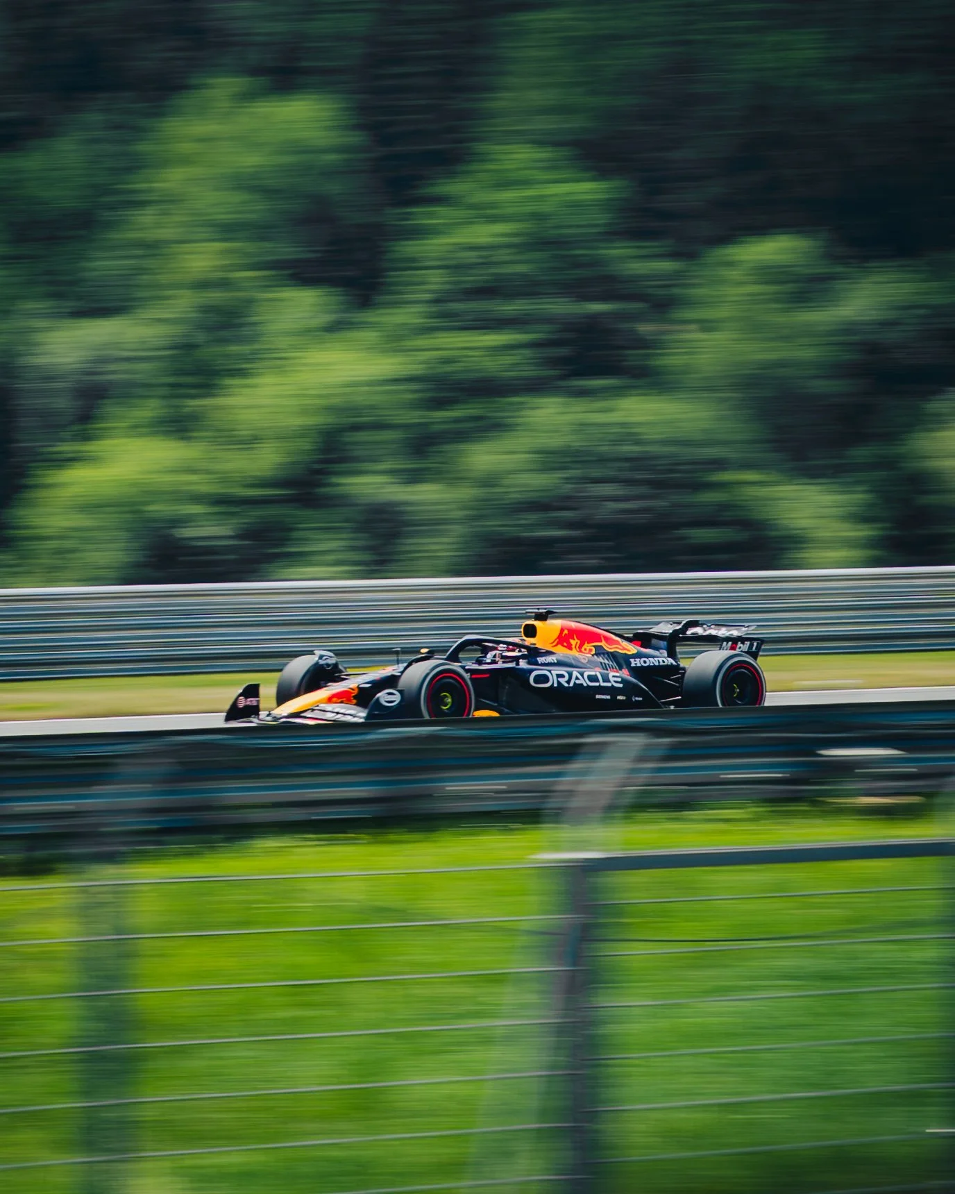 Ein Rennwagen auf einer Rennstrecke, mit Logos von Red Bull, Oracle, Honda und Mobil 1, fährt bei hoher Geschwindigkeit.