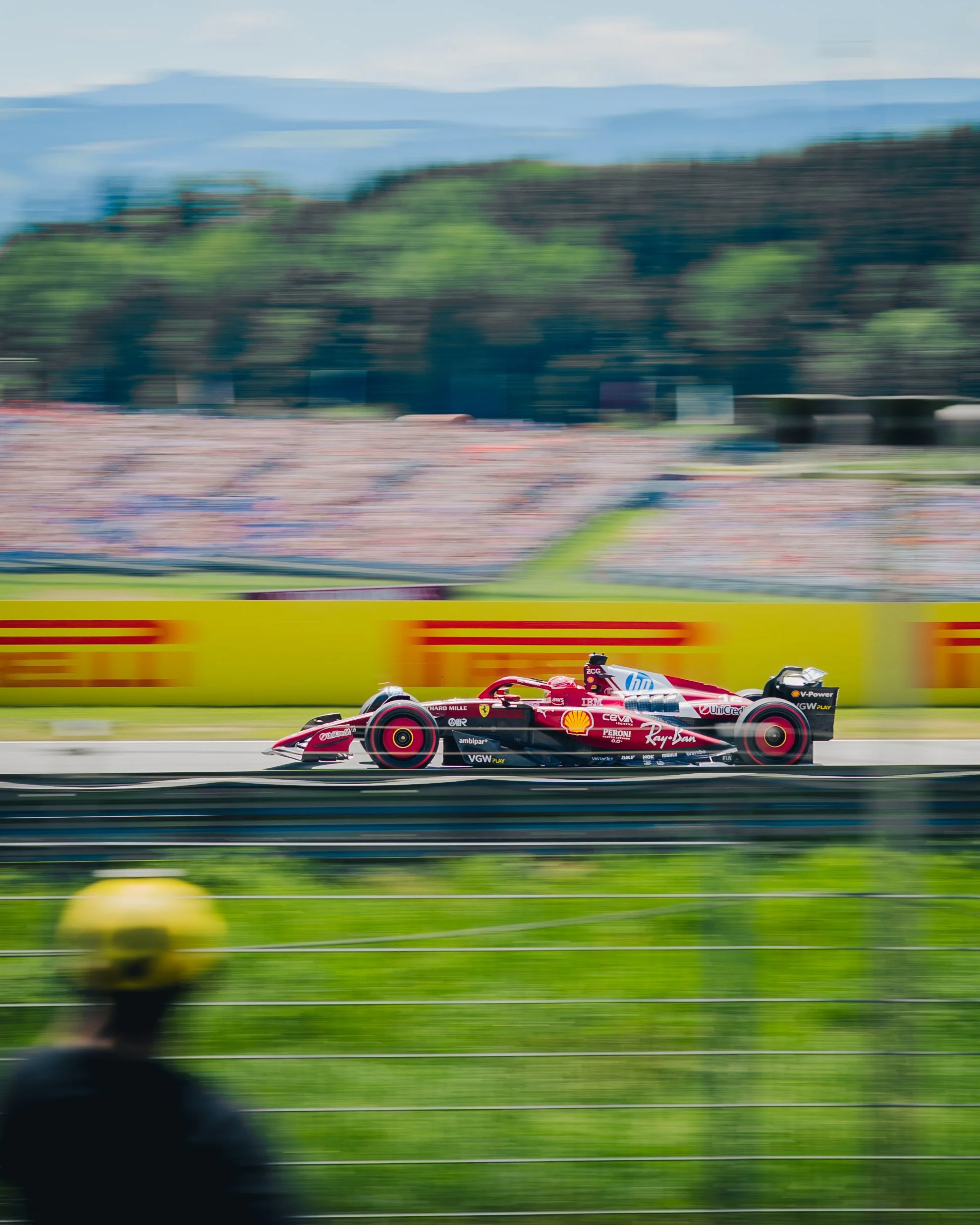 Formel 1 Rennwagen auf der Rennstrecke während des Rennens, mit Zuschauern im Hintergrund.