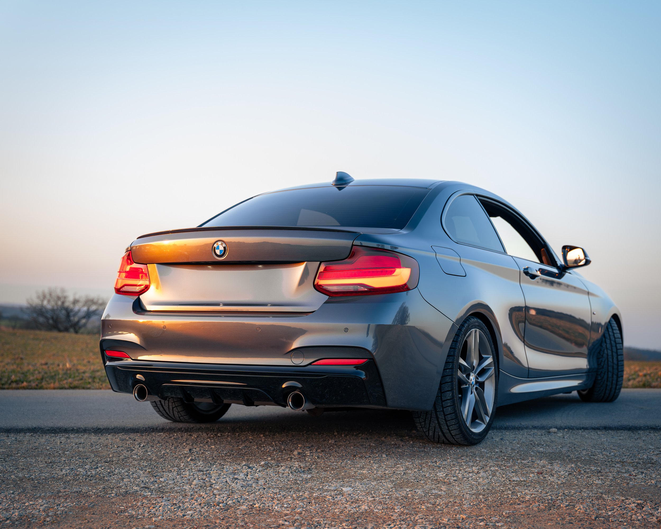 Schwarz lackierter BMW-Kabriolett auf freiem Feld bei Sonnenuntergang