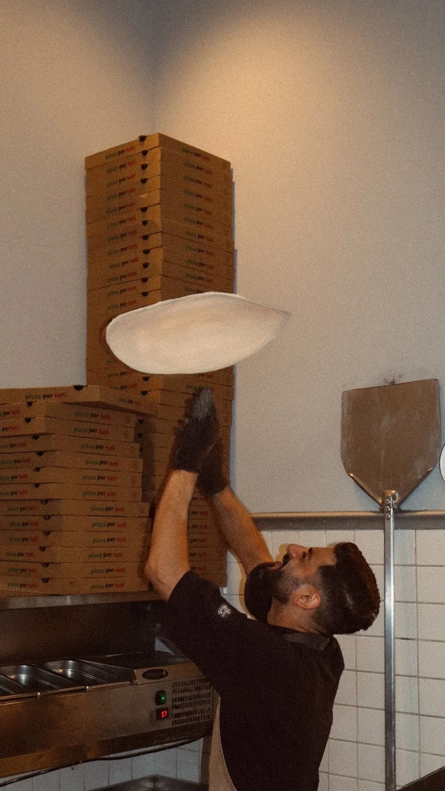 Man pakt een pizzadoos van een stapel pizza dozen in een keuken.