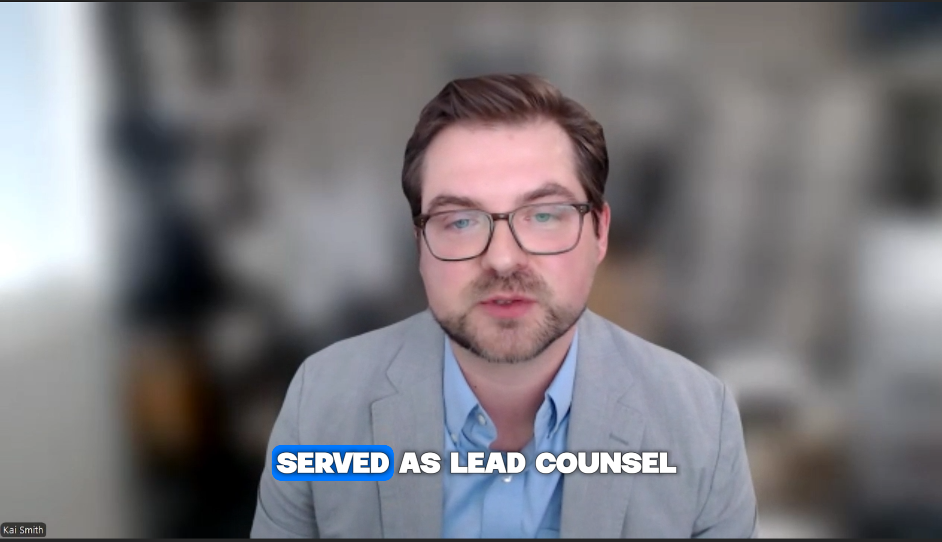 A man with glasses and a beard wearing a gray blazer and light blue shirt speaking during a virtual meeting. Caption reads "Served as Lead Counsel."
