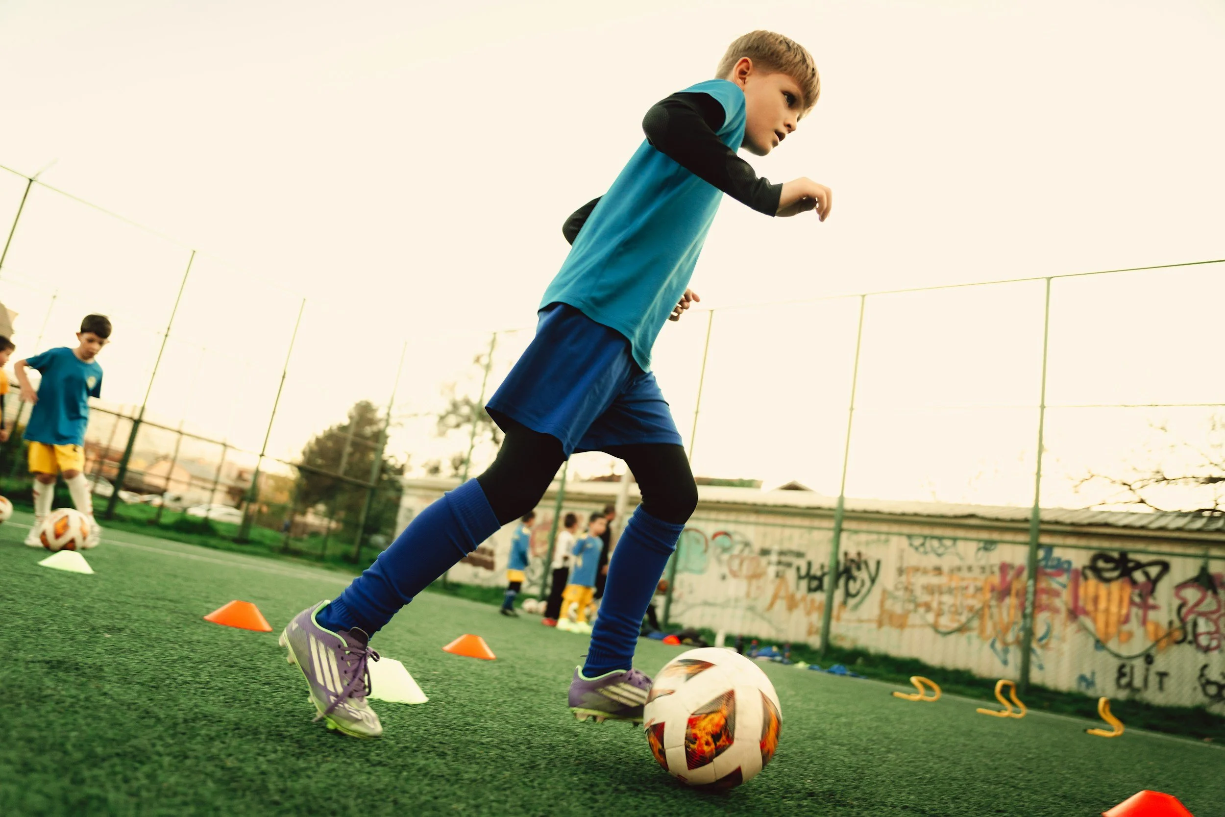 Young boy playing soccer with determination, representing persistence, resilience, confidence, and the development of a growth mindset in children.