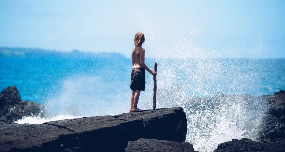 Hilo child standing on the shore overlooking Hilo Bay.