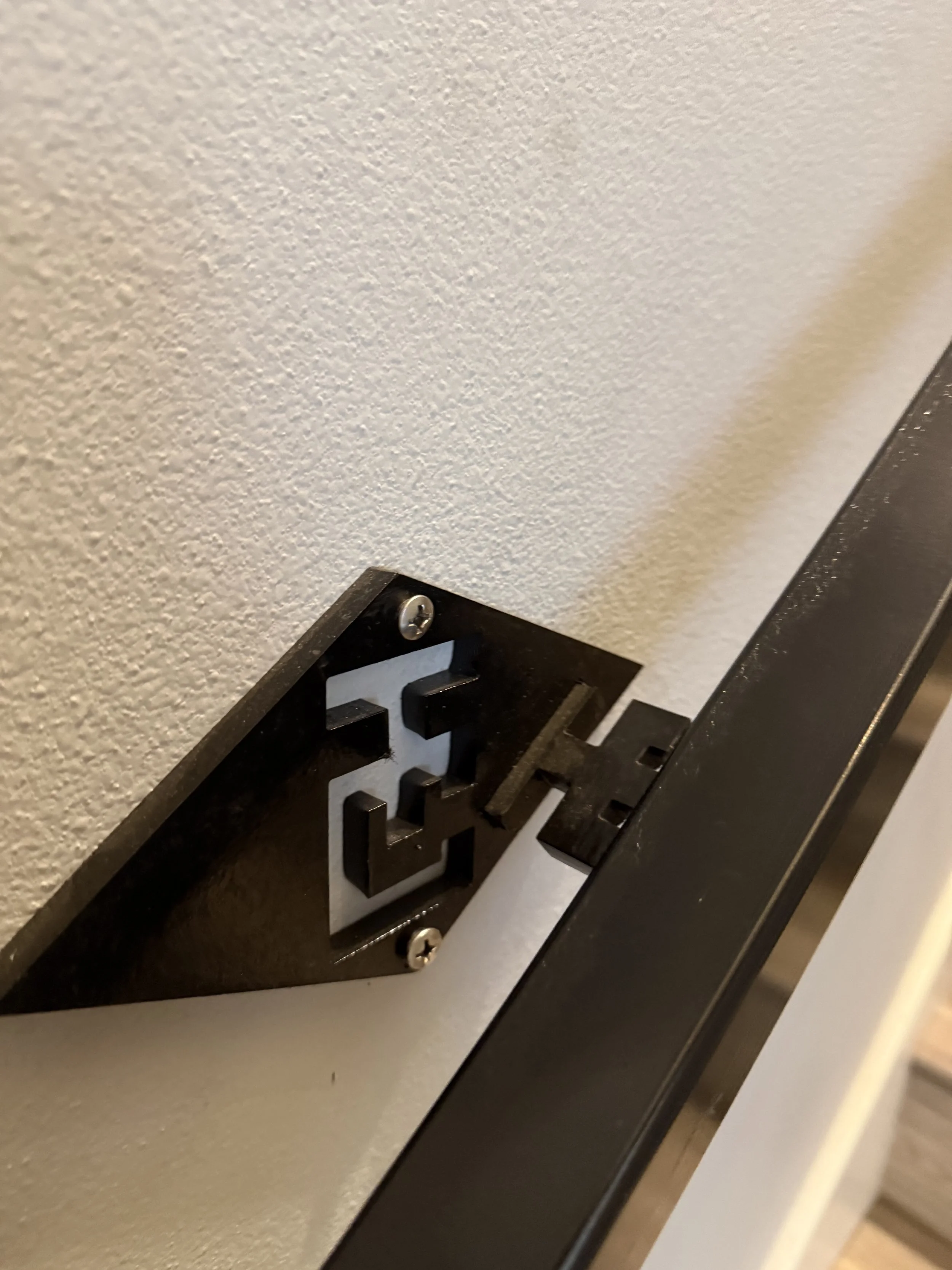 Close-up of a black wall plate socket missing its outlet cover, exposed electrical outlet opening on a white wall.