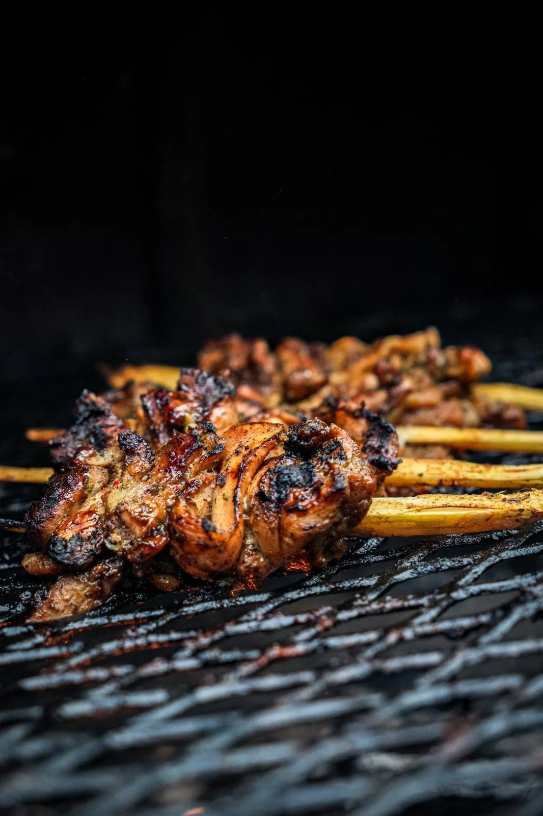 Close-up of grilled skewers with meat cooking on a barbecue grill.