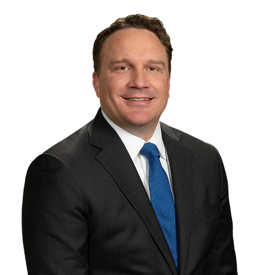 A professional man with short brown hair wearing a dark suit, white shirt, and blue tie, smiling at the camera.