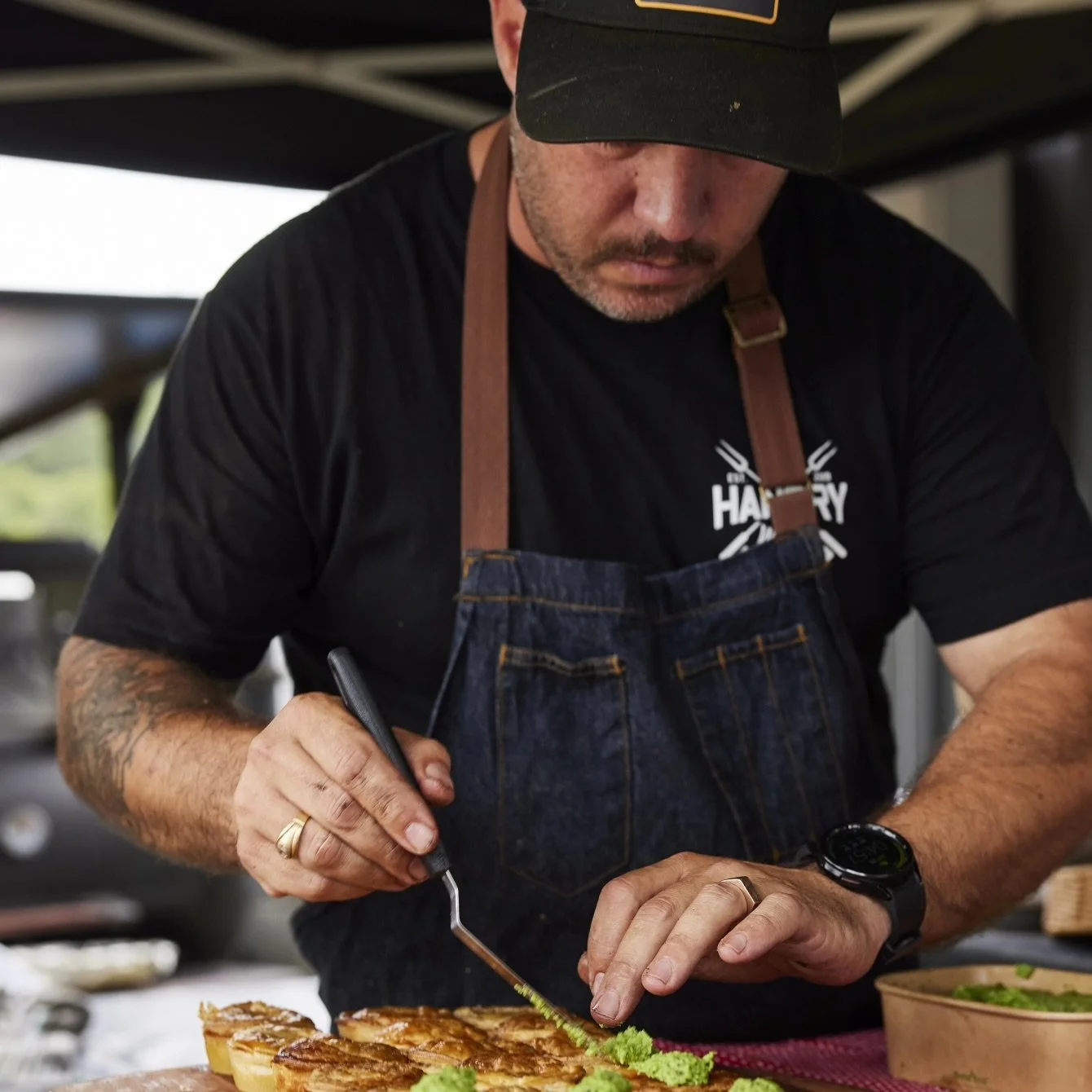 Cedric Lopez, from Hangry Wolf preparing food, using tweezers to garnish a dish for a wedding platter.