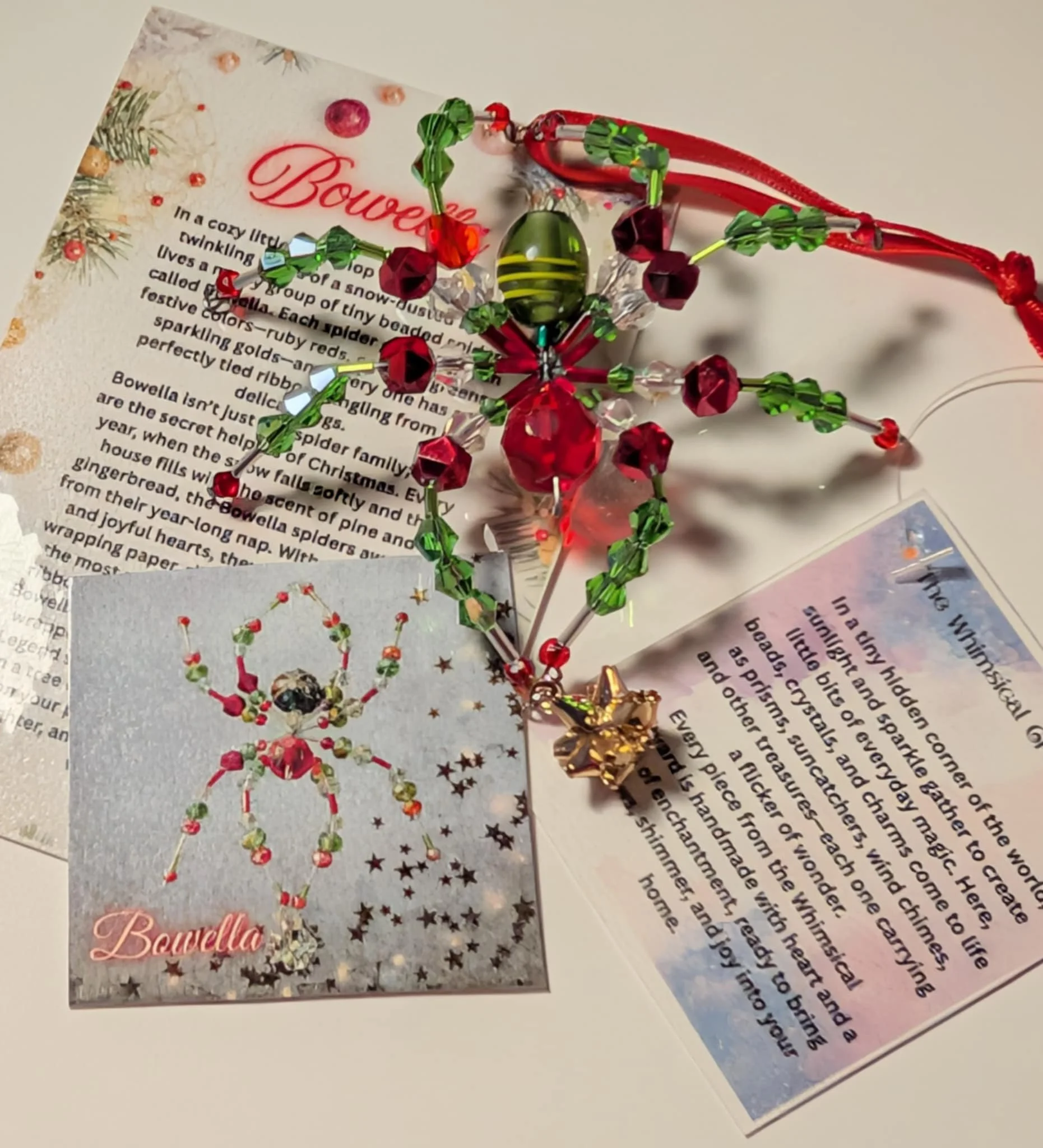 Photo of a Christmas decoration consisting of a beaded ornament with red, green, and pink beads, a red string, and a gold star charm, placed on top of some printed pages and a postcard.
