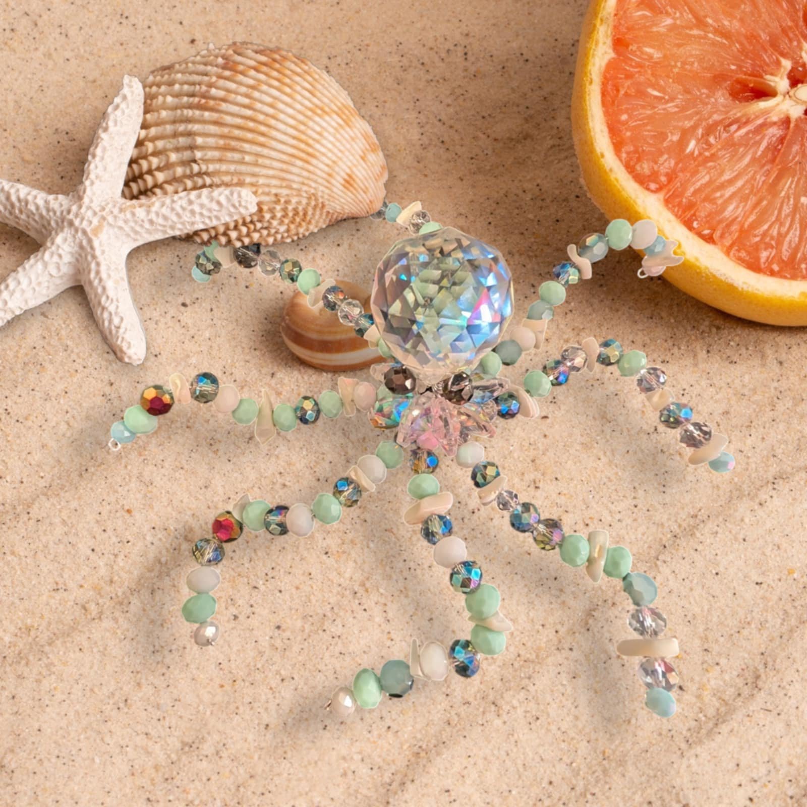 Jewelry, seashells, starfish, and a grapefruit slice on sand beach.