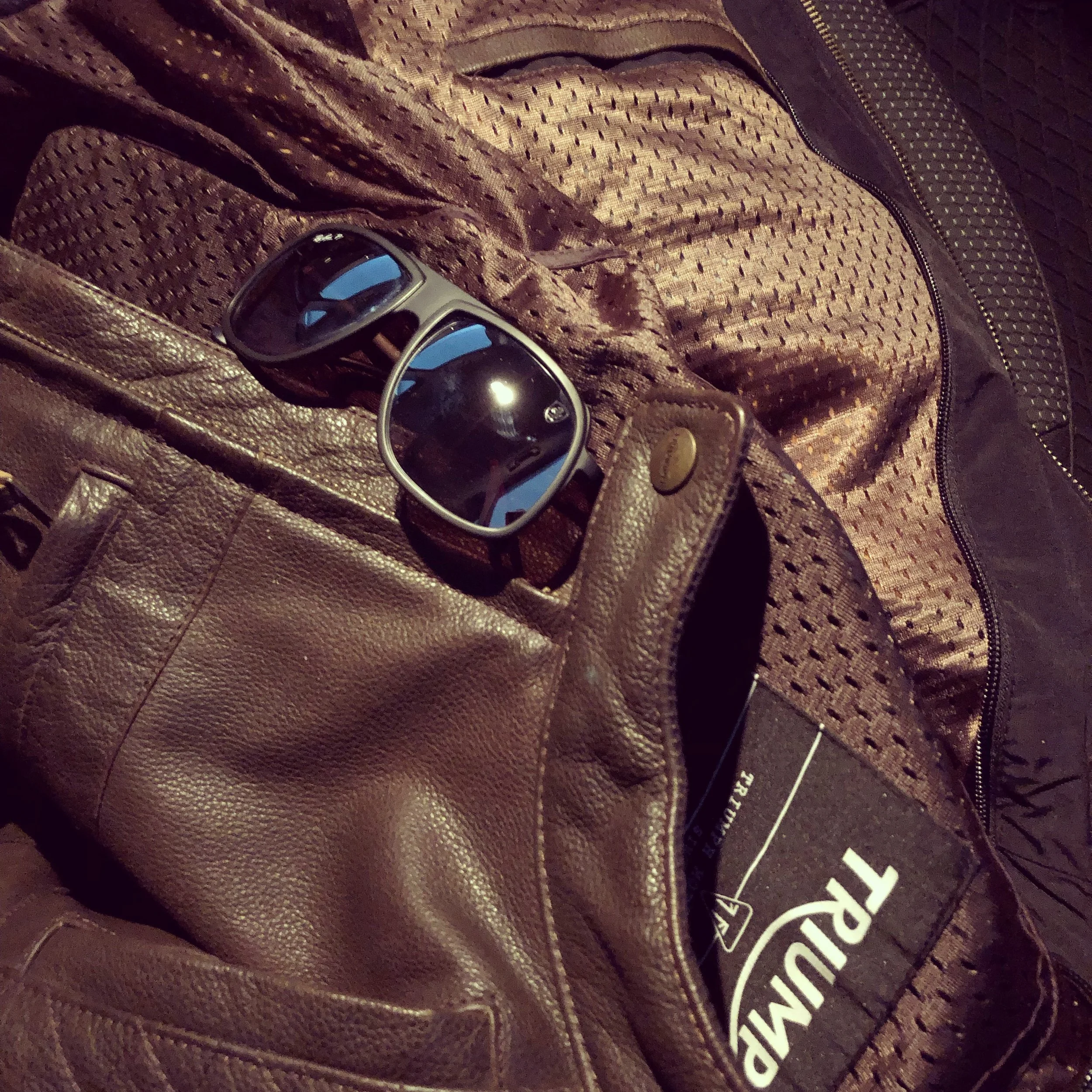 A brown leather jacket with a pair of black sunglasses resting on top of it