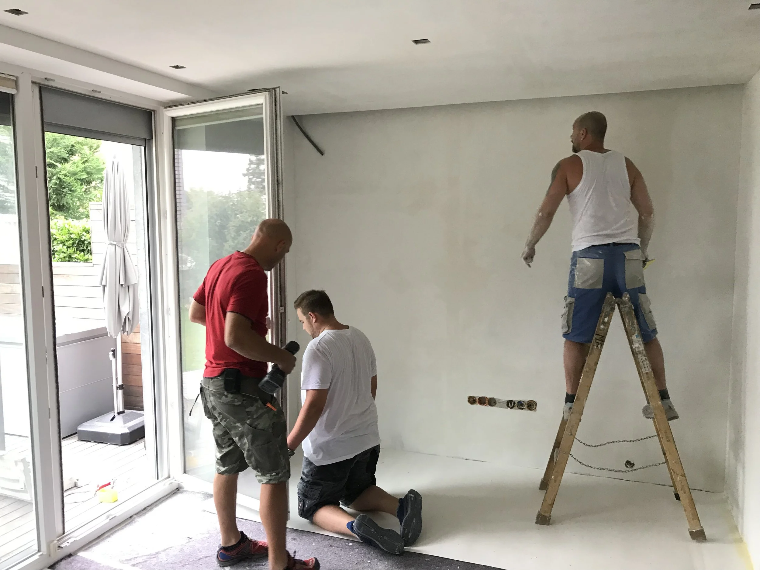 Innenausbau auf der Baustelle: 3 Handwerker bei der Wandvorbereitung, Spachtelarbeiten im Wohnraum - Paddy Artist Raumausstattung und Interior Design, Wien, Österreich