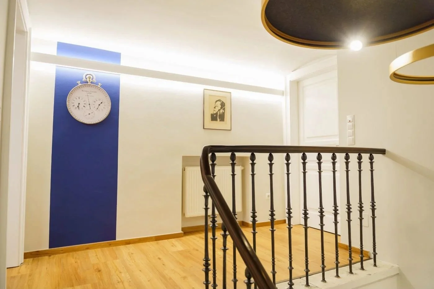 Nachher-Bild eines modernisierten Stiegenaufgangs im Altbau mit warmweißem Licht, offener Raumwirkung und wohnlicher Atmosphäre