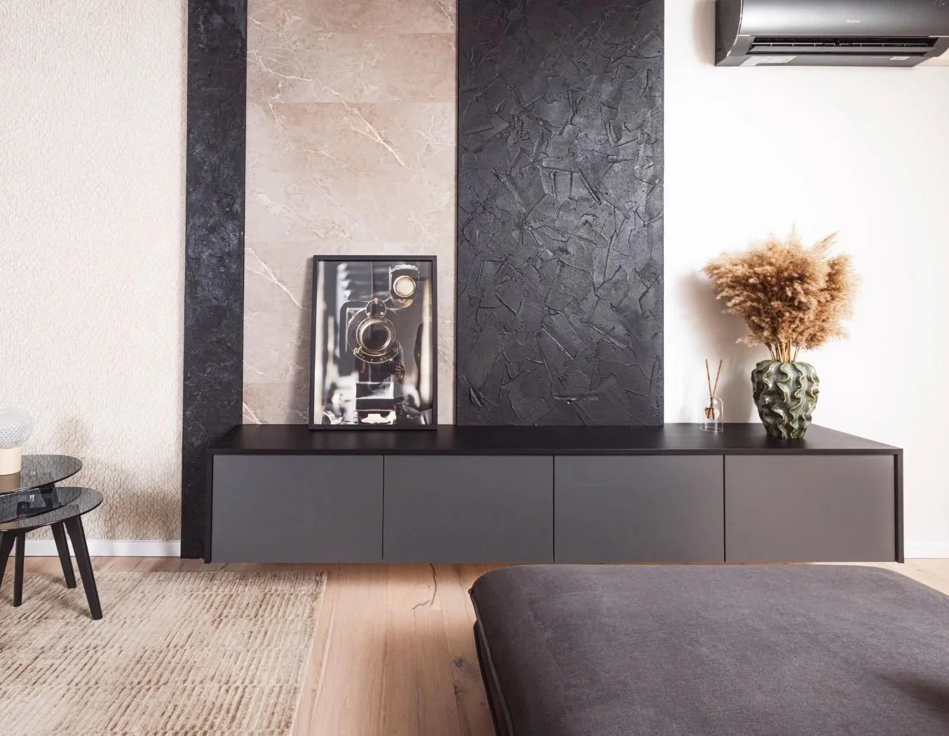 Dunkles Sideboard vor einer strukturierten Akzentwand mit Kunstbild und Blumenvase