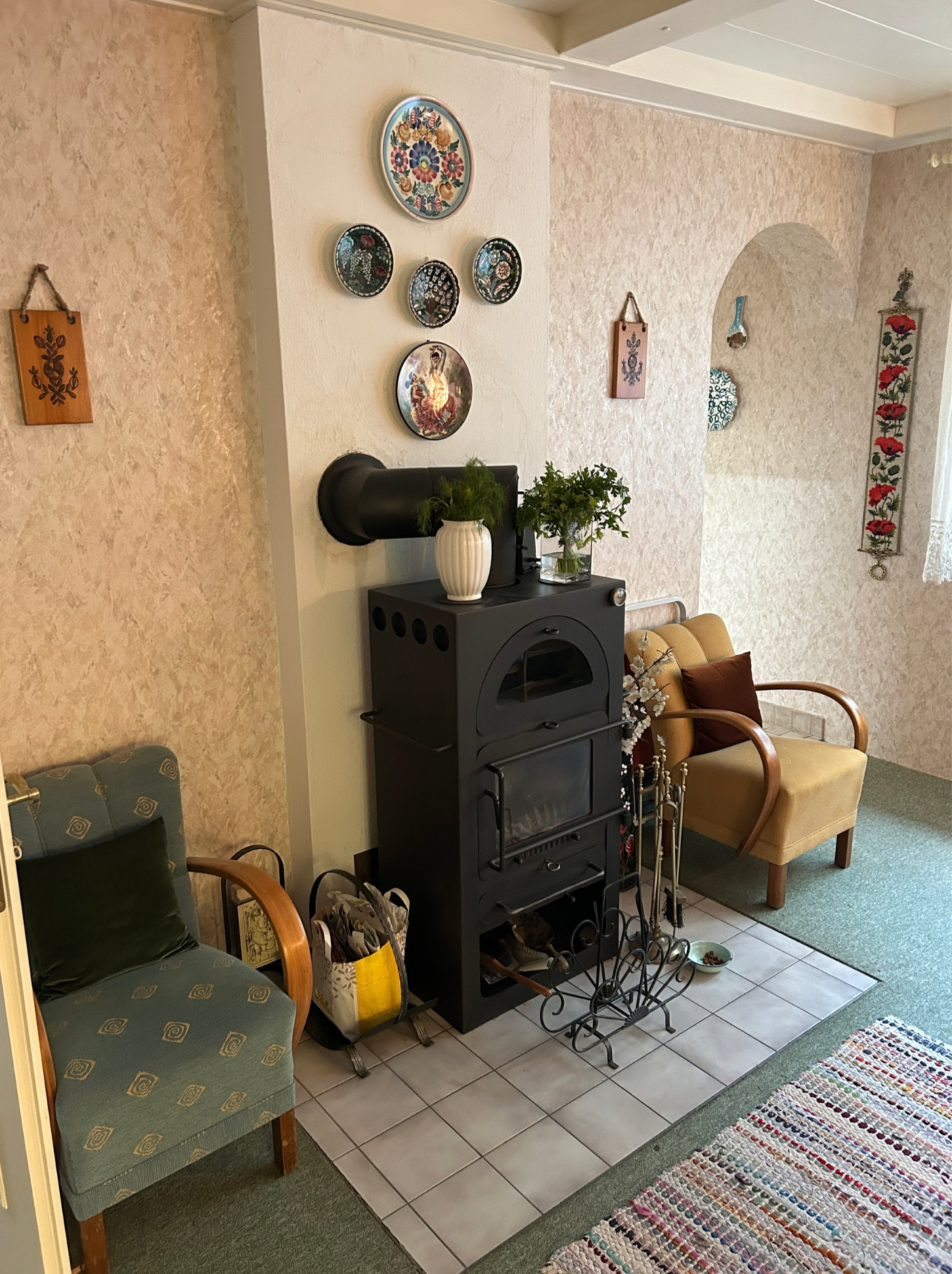 Vorher-Bild eines Wohnbereichs mit Kachelofen, Sitzmöbeln und klassischer Bestandsgestaltung vor der Modernisierung