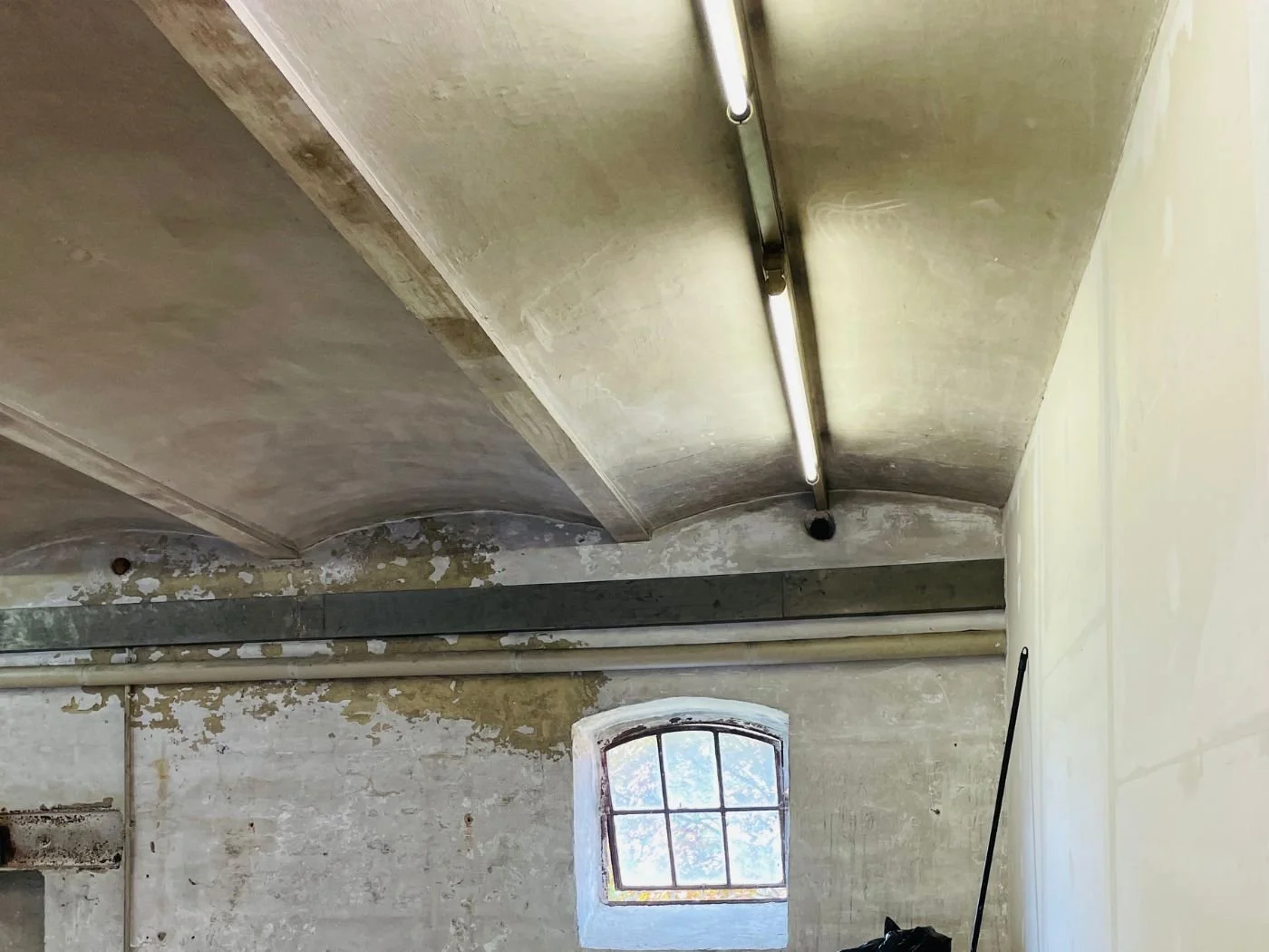 Vorher-Bild eines sanierungsbedürftigen Innenraums mit alter Decke, sichtbaren Gebrauchsspuren und roher Wandstruktur vor der Renovierung