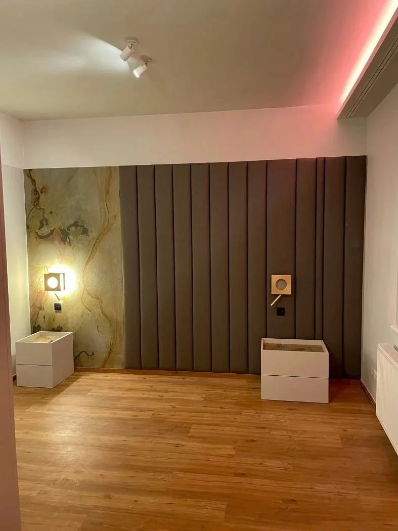Modernes Schlafzimmer nach Renovierung: Akustikpaneel und Lederpaneel an der Wand, neuer Parkettboden, montierte Nachttische - moderne Renovierung der Paddy Artist Design GmbH